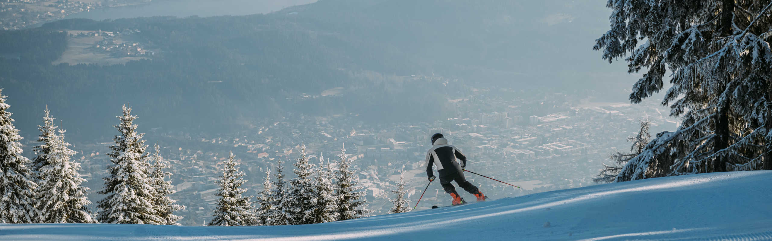Skifahren am Goldeck mit Aussicht auf Spittal an der Drau und verschneite Wälder.