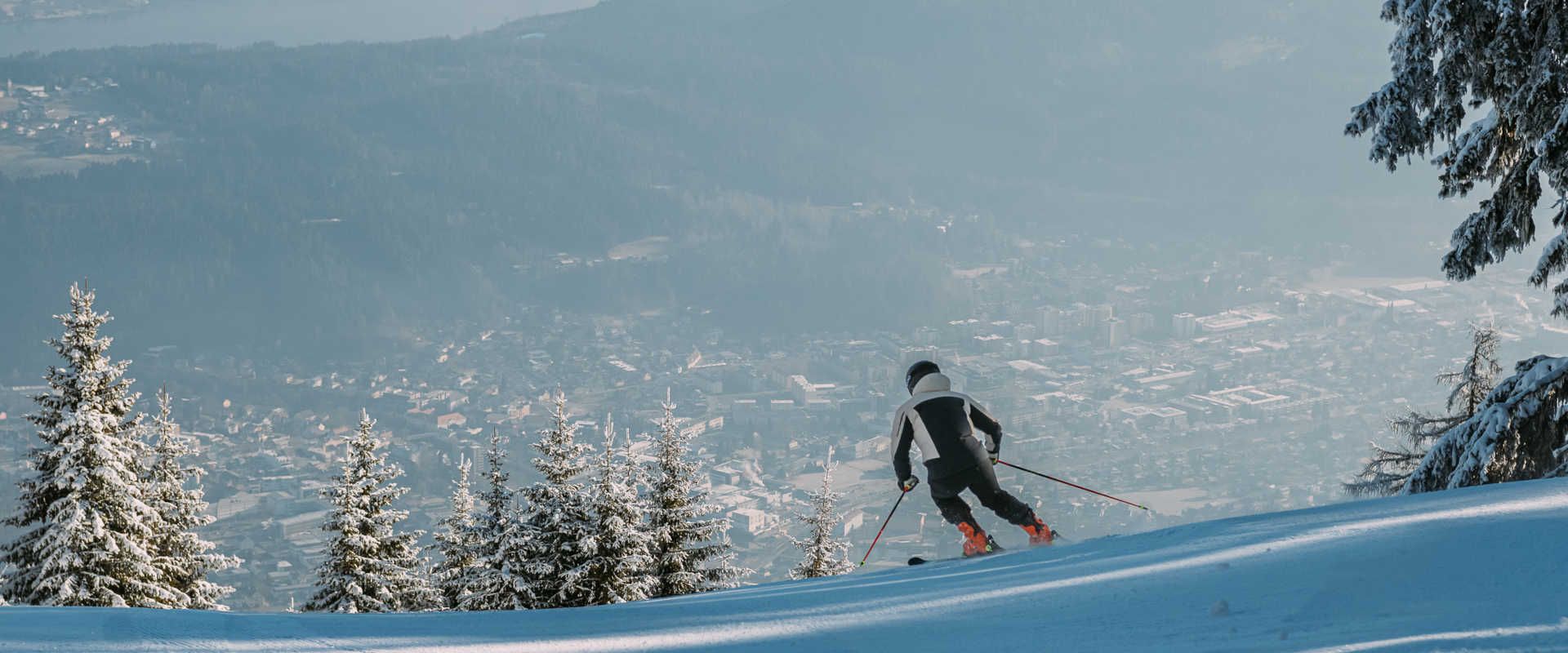Skifahren am Goldeck mit Aussicht auf Spittal an der Drau und verschneite Wälder.