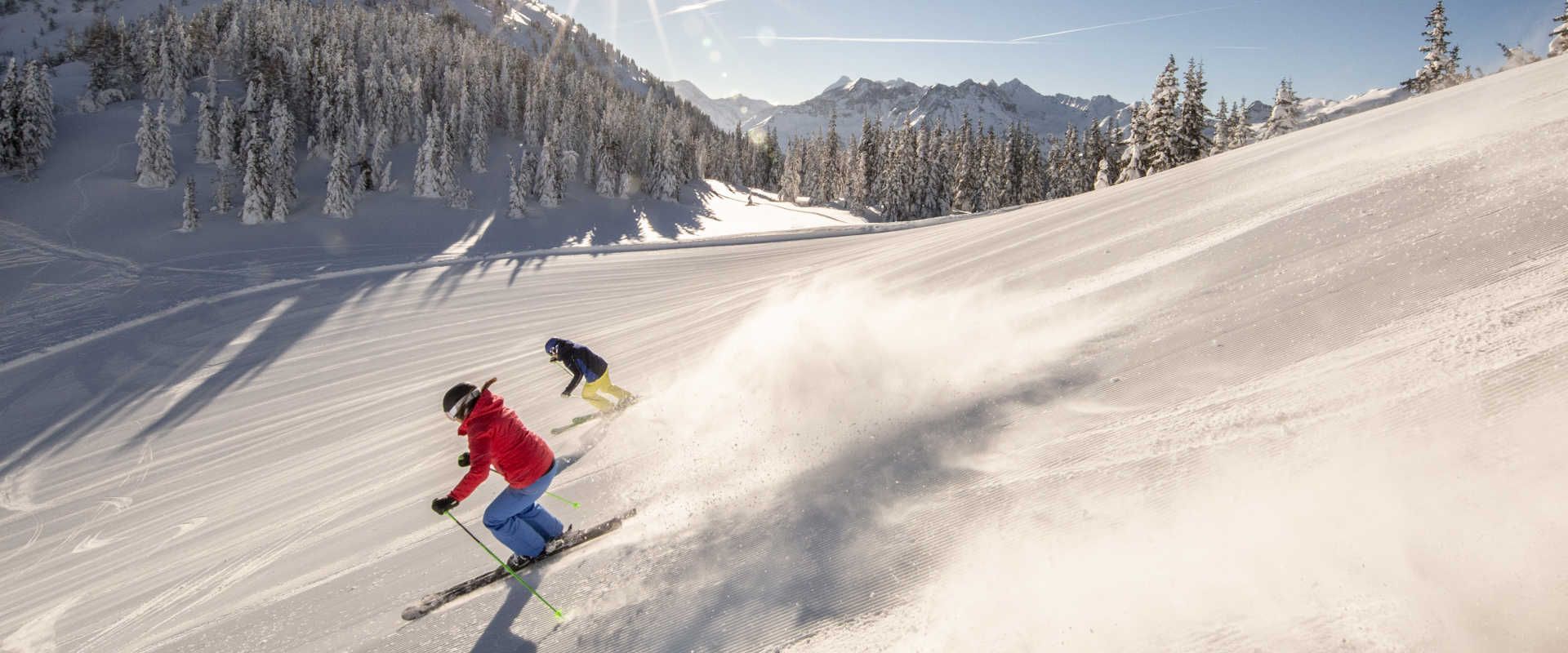 Two skiers on the Planai in Schladming carving on a freshly groomed slope in the Schladming-Dachstein region.