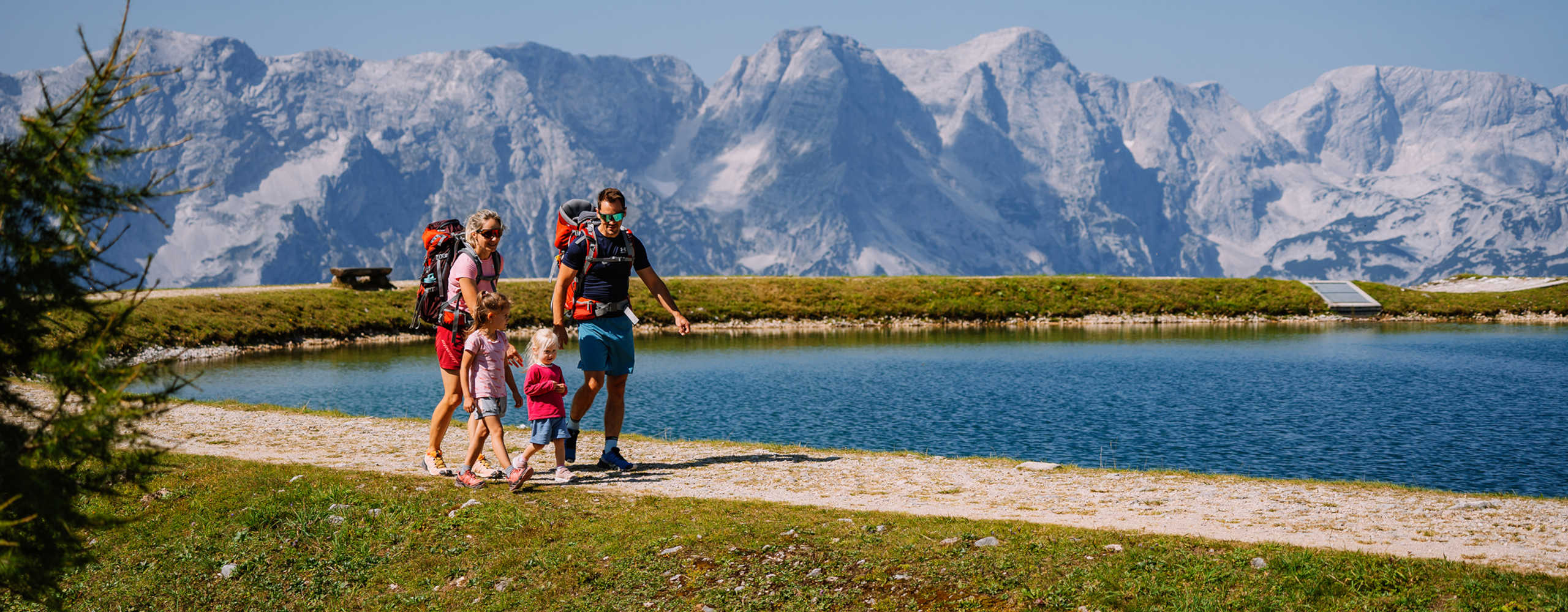 Family hike in summer in Hinterstoder with a lake in the background