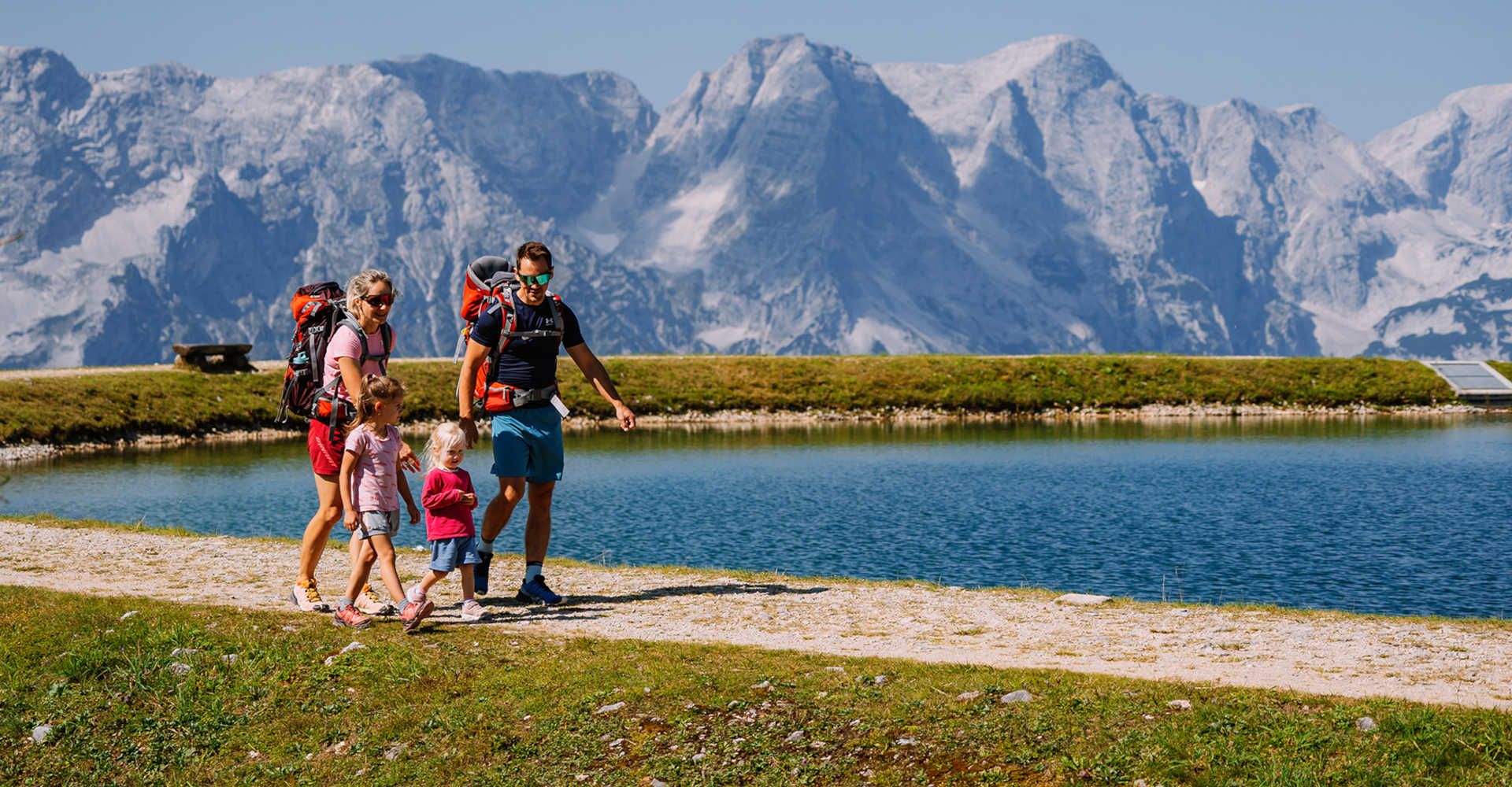Family hike in summer in Hinterstoder with a lake in the background
