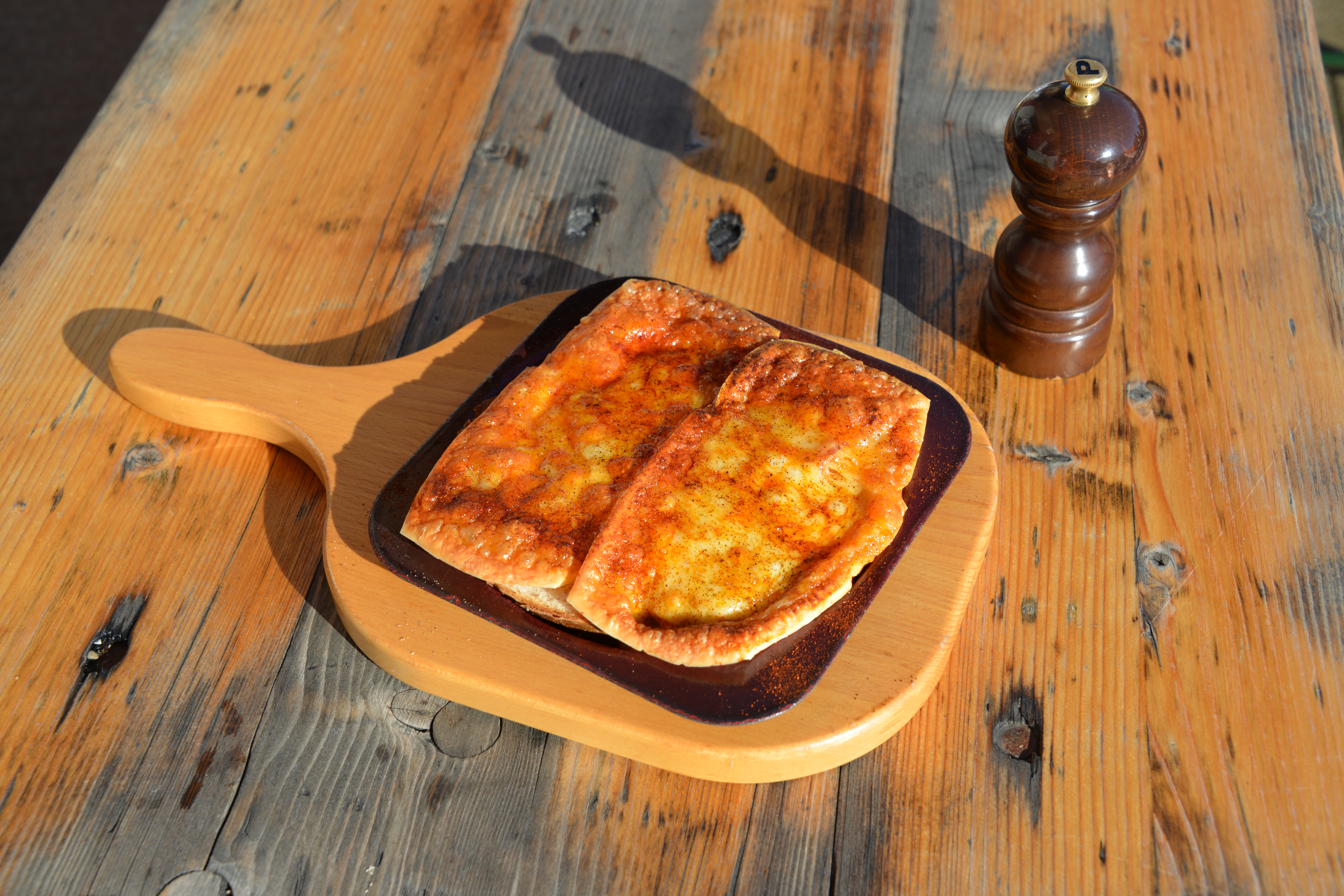 Käseschnitte auf einem Holzbrett serviert auf einem rustikalen Tisch.