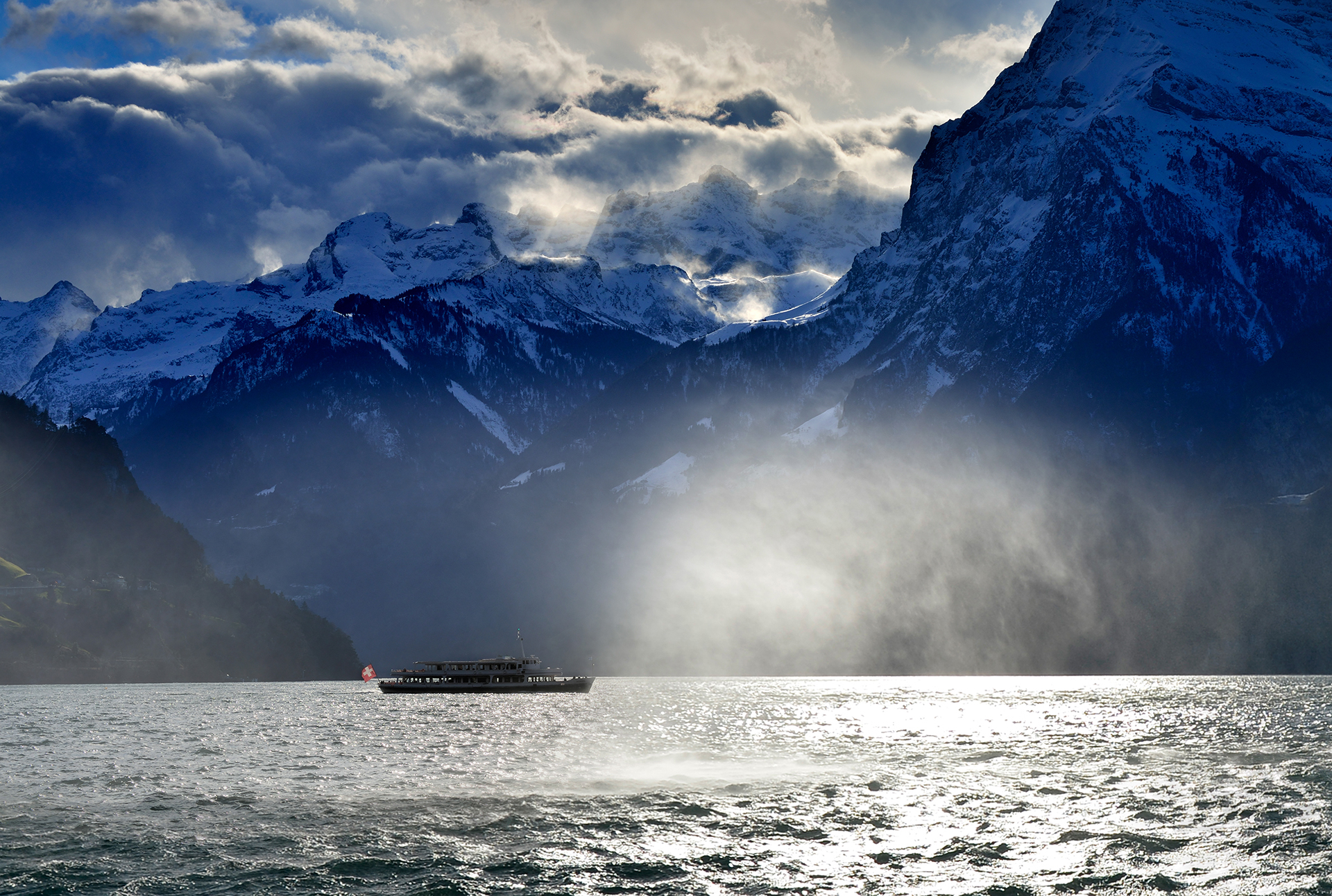 Image d'ambiance avec nuages et brouillard du lac des Quatre-Cantons en hiver avec un bateau à moteur.