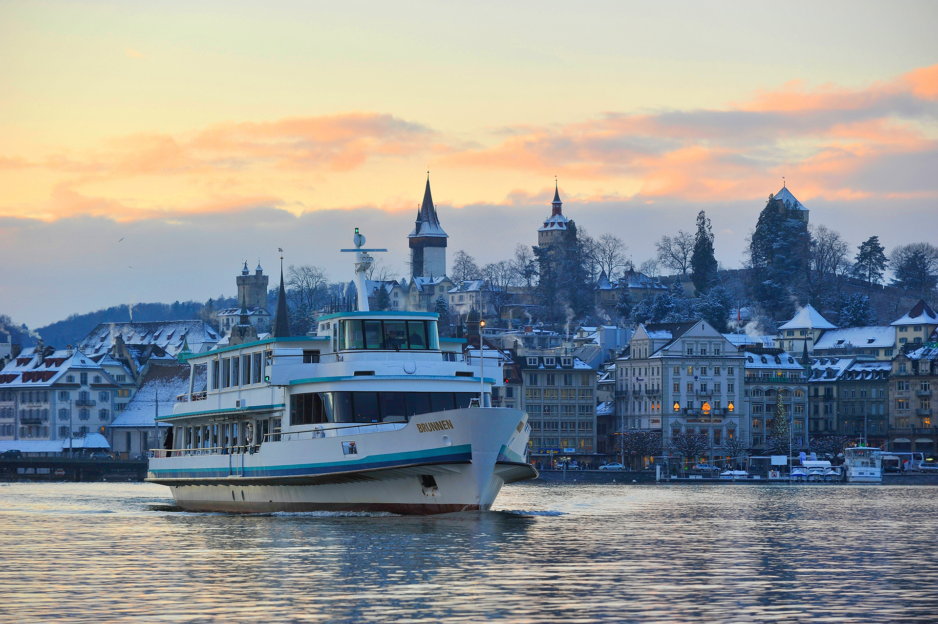Bateau à moteur devant la ville de Lucerne en hiver, dans l'ambiance du soir.
