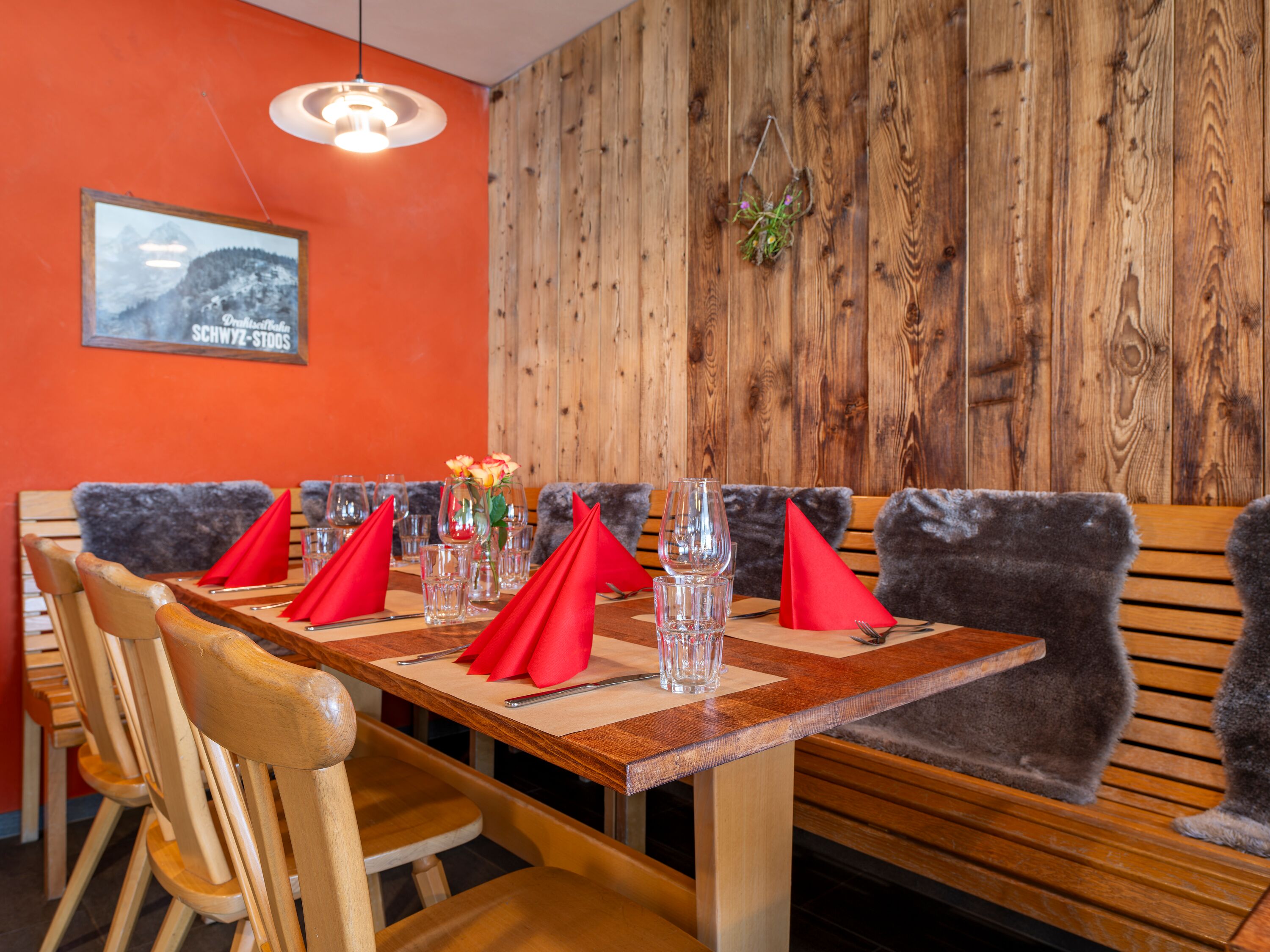 Cozy restaurant area with wooden walls, bench seating, and a set table.
