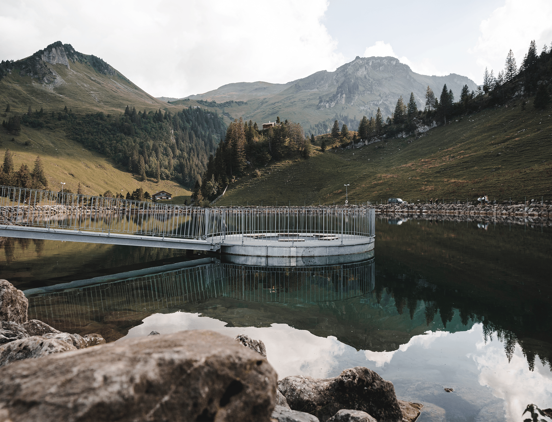 Calm mountain lake with clear water, surrounded by mountains and alpine landscape.