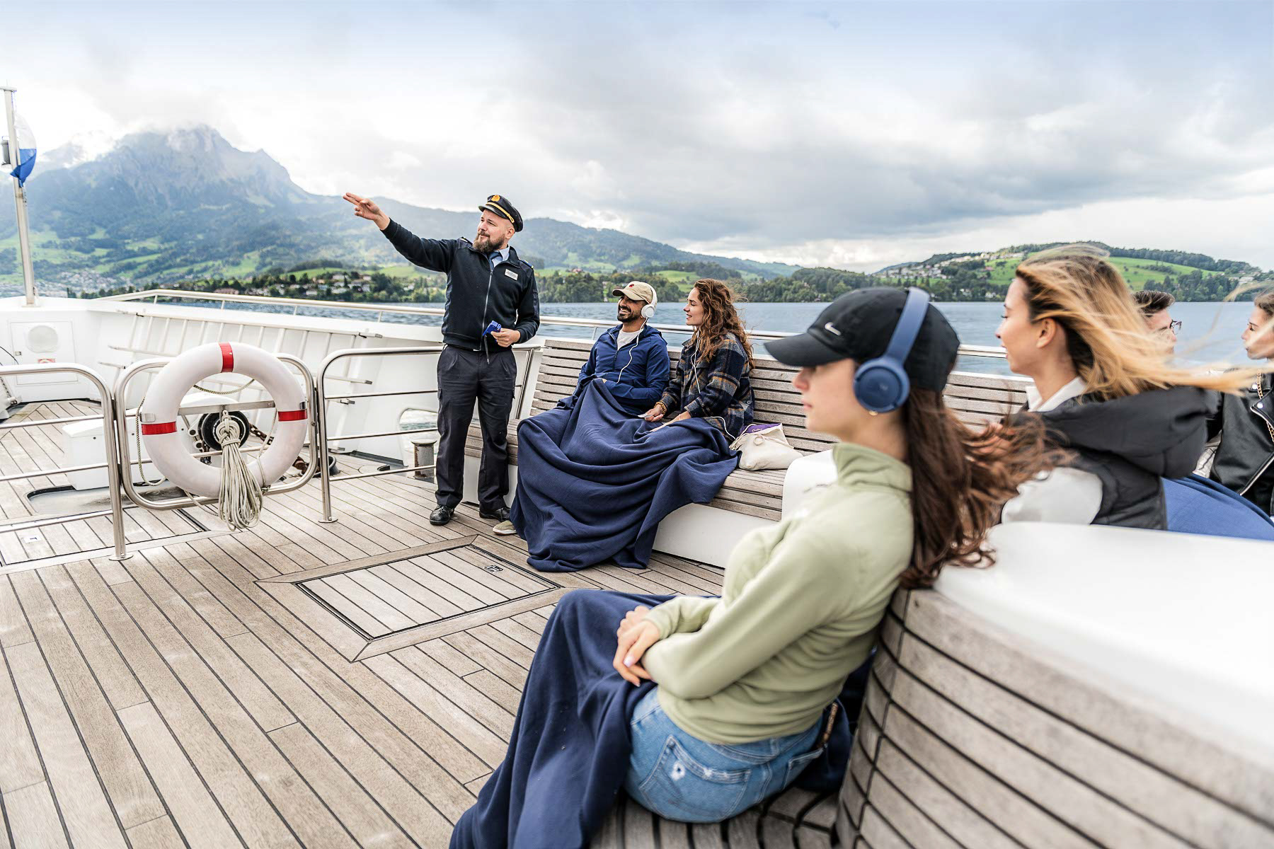 Passagers avec audioguide sur le pont d’un bateau lors de la croisière panoramique sur le lac des Quatre-Cantons.
