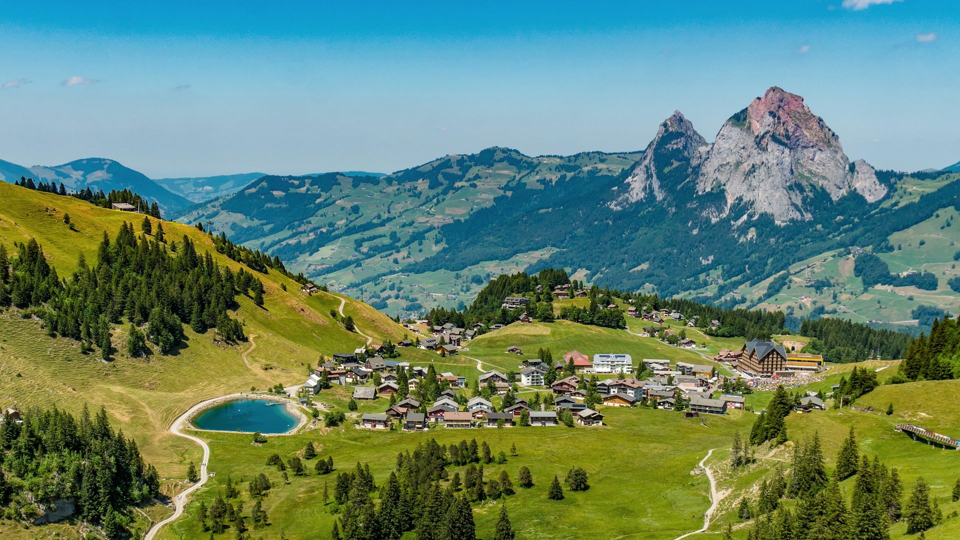 Bergdorf Stoos mit alpiner Landschaft, kleinem Bergsee und Blick auf markante Gipfel.