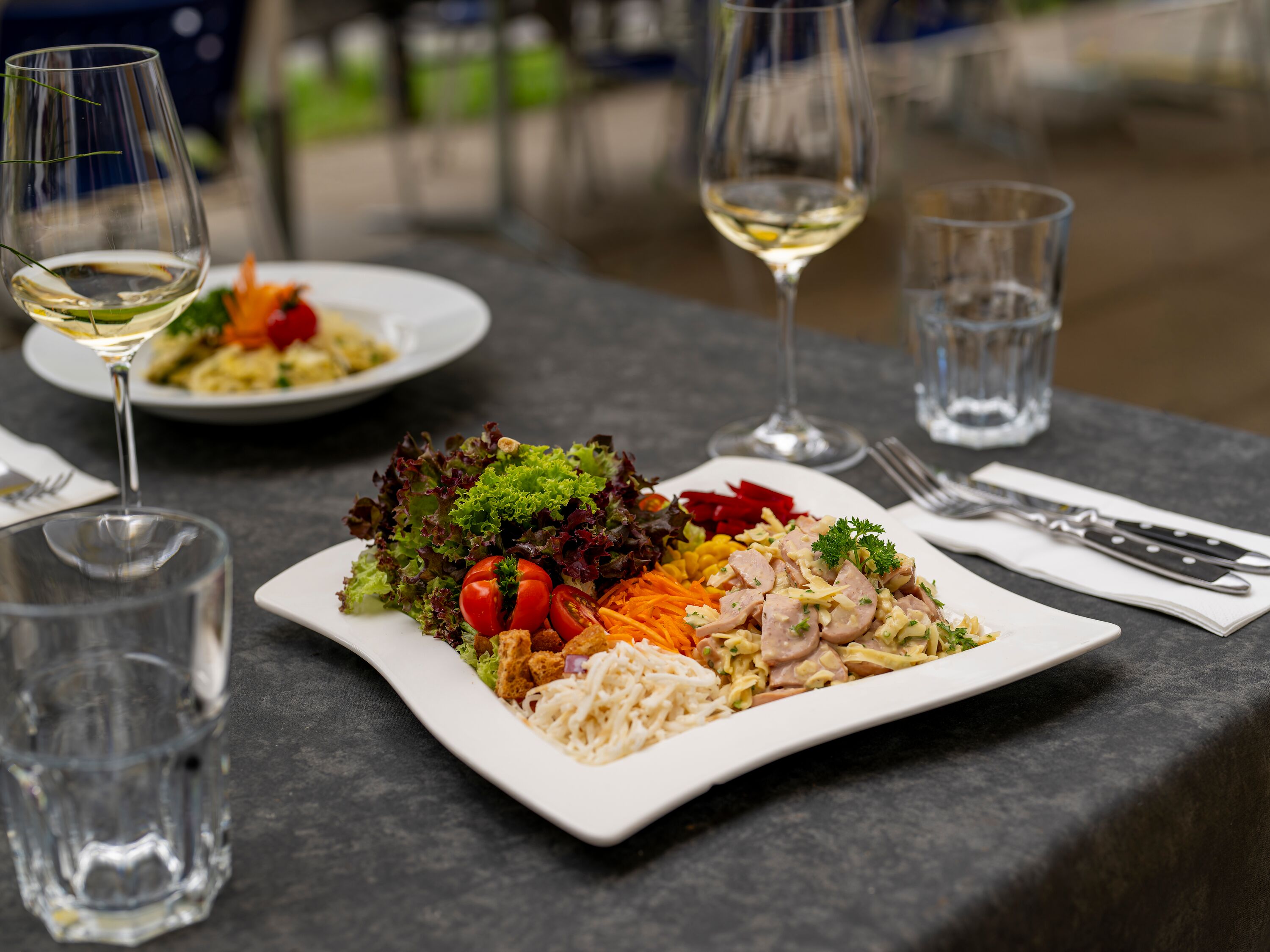 Served plate with meat, vegetables, and side dishes on a set table in a restaurant.