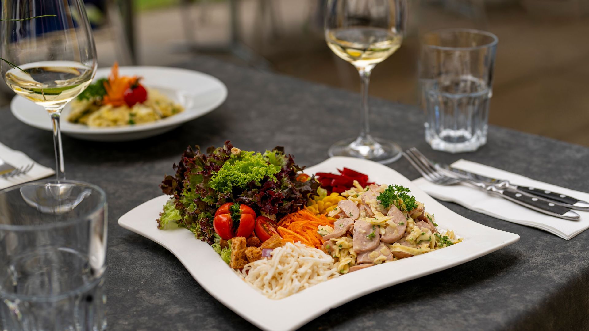 Served plate with meat, vegetables, and side dishes on a set table in a restaurant.