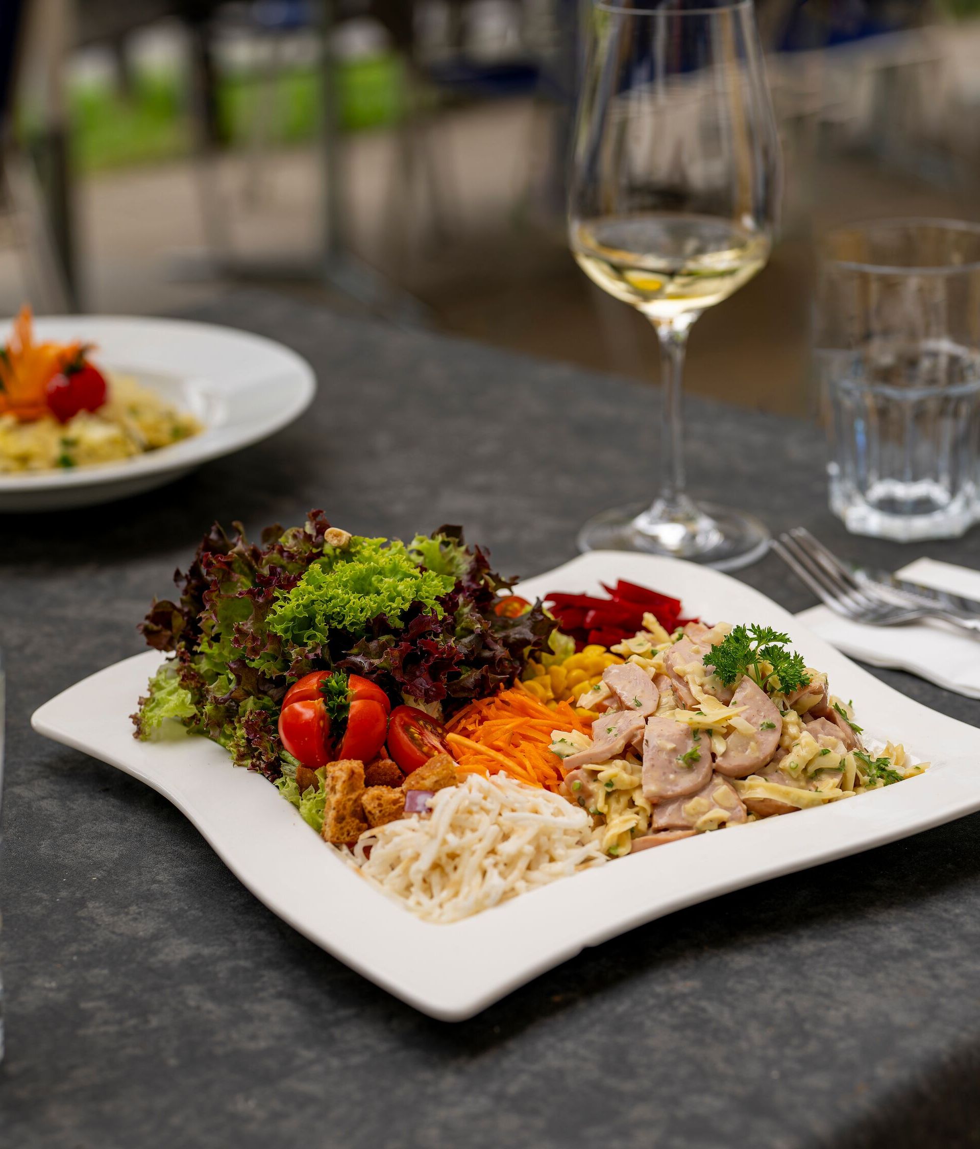 Servierter Teller mit Fleisch, Gemüse und Beilagen auf einem gedeckten Tisch im Restaurant.