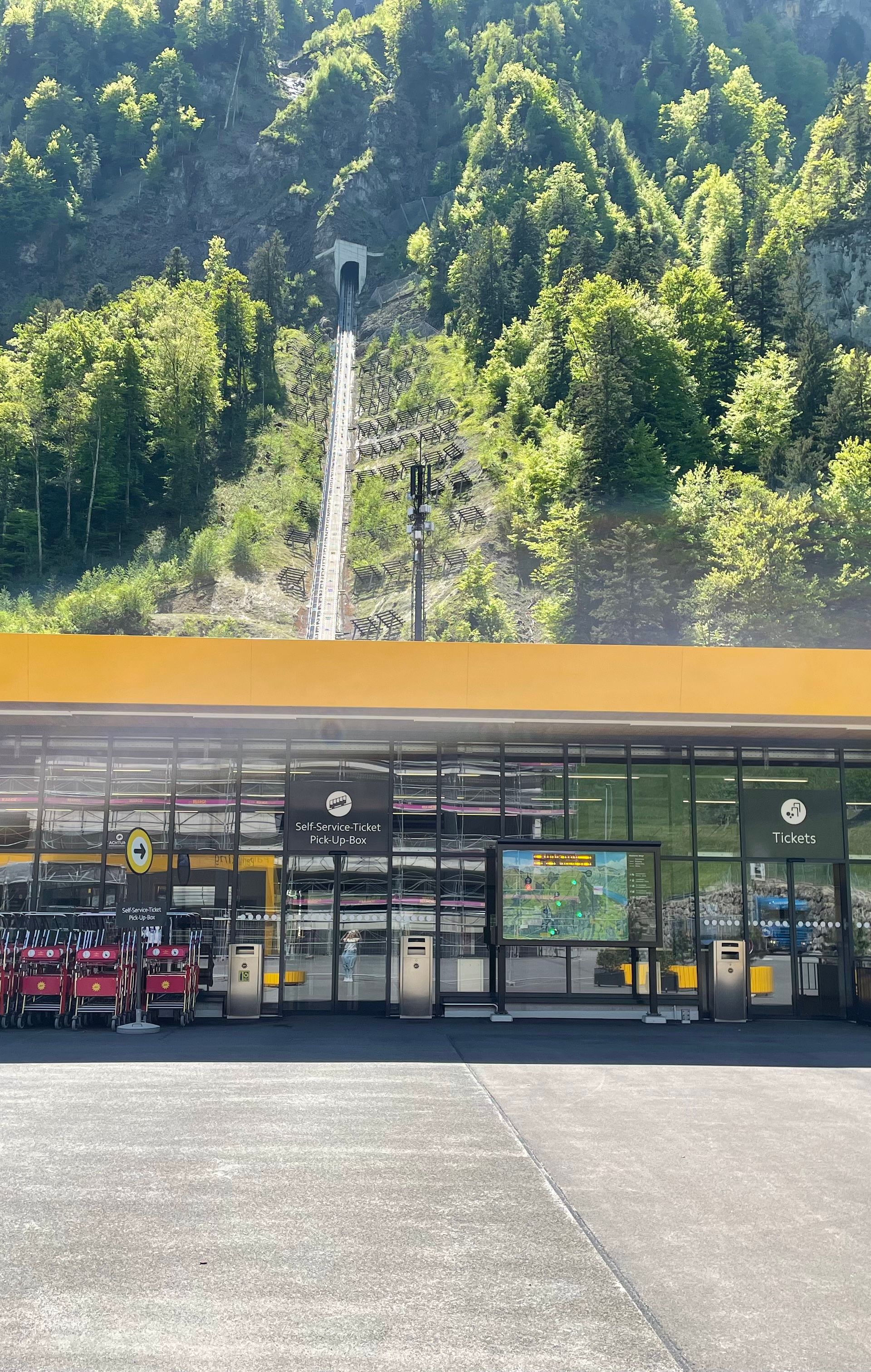 Talstation der Standseilbahn Schwyz–Stoos mit moderner Architektur und Blick auf die Bahnstrecke.