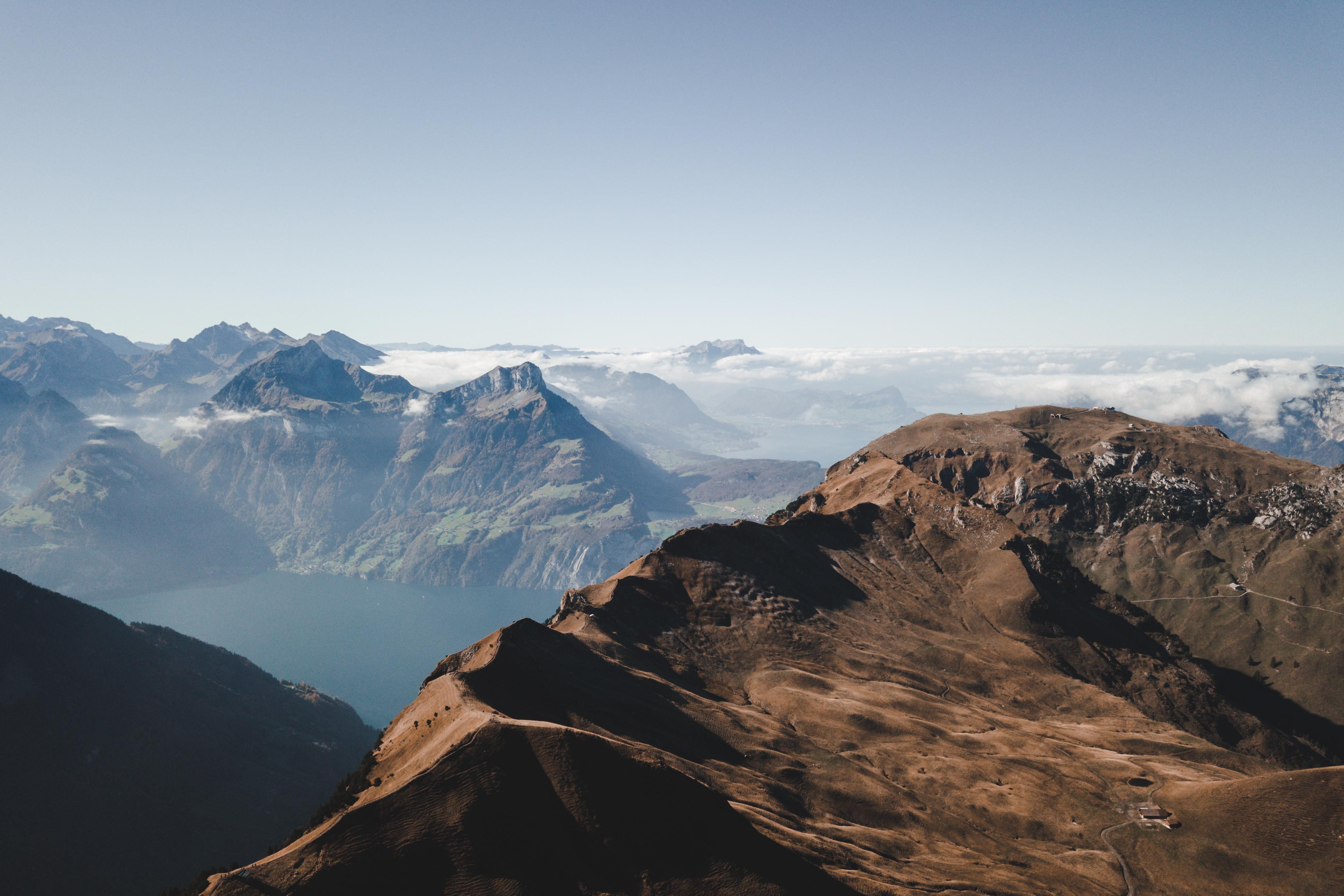 Mountain ridge with rocky terrain overlooking Lake Lucerne and the surrounding Alps.