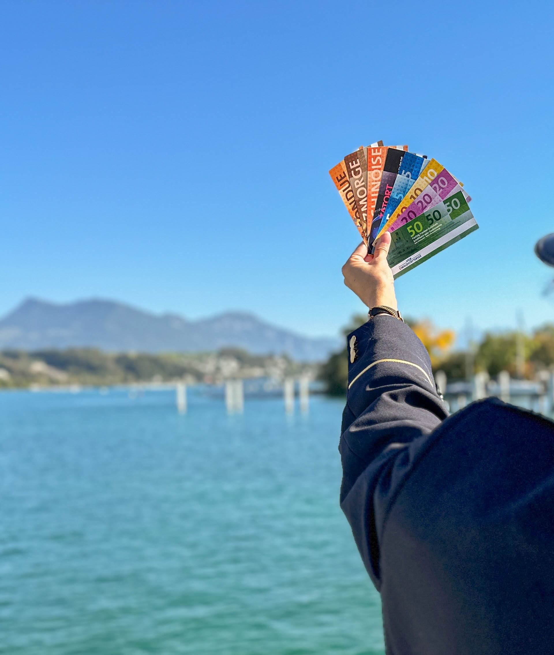 Bild mit einer Person, die die Gutscheine in den Himmel hebt und im Hintergrund sieht man den Vierwaldstättersee und die Bergwelt.
