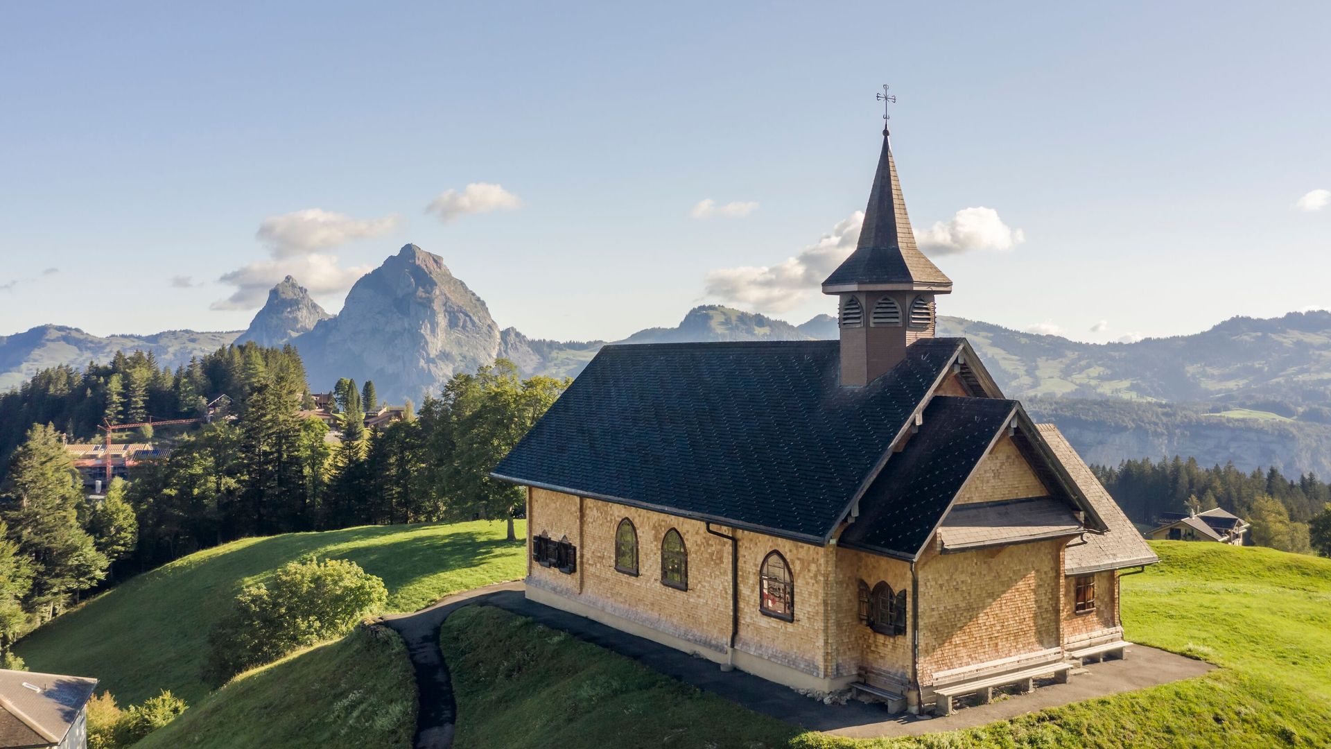 Kapelle auf einem Hügel in alpiner Landschaft mit Blick auf umliegende Berge.