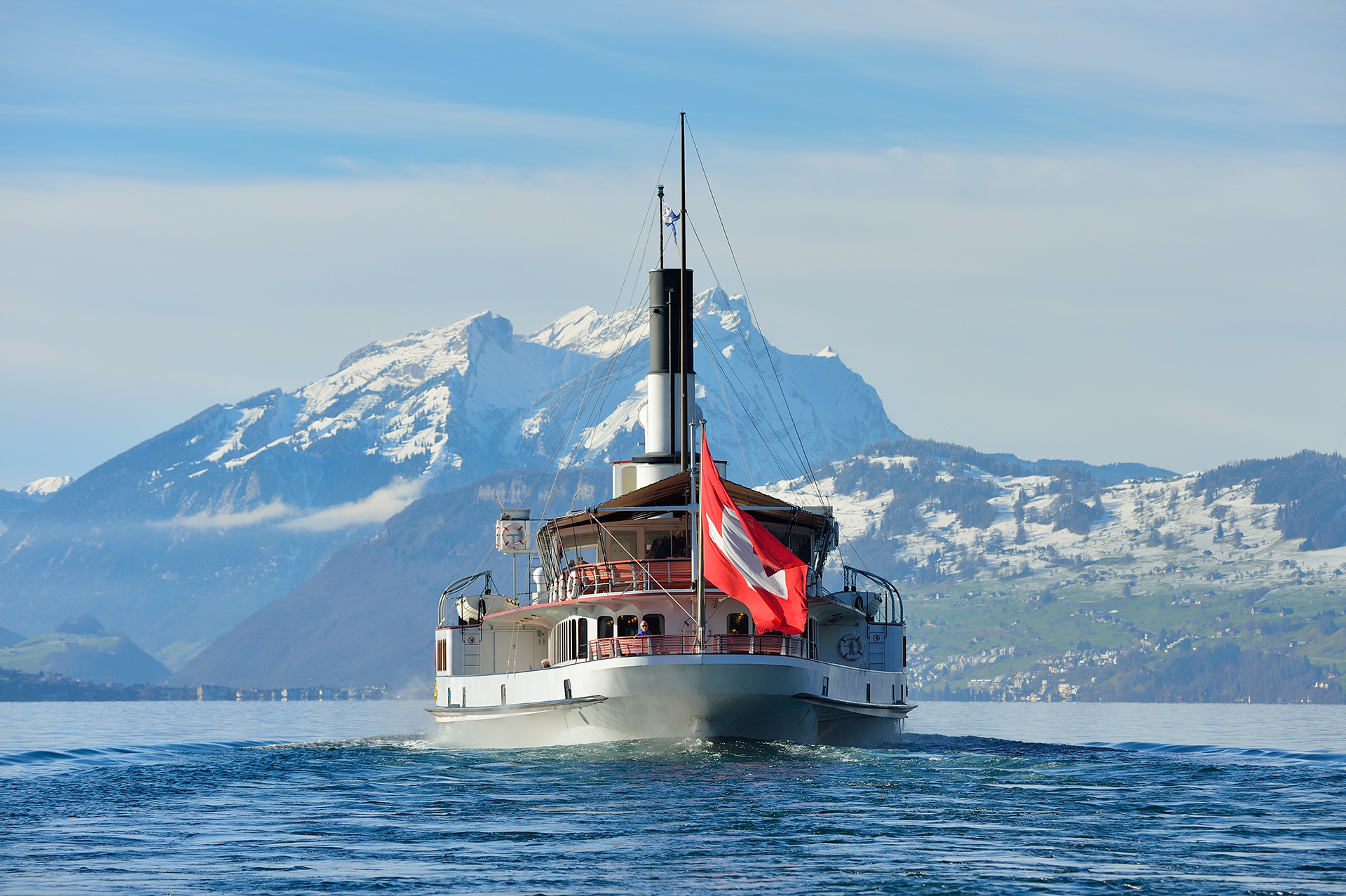 Dampfschiff Uri von hinten an einem sonnigen Wintertag auf dem Vierwaldstättersee vor dem Pilatus.