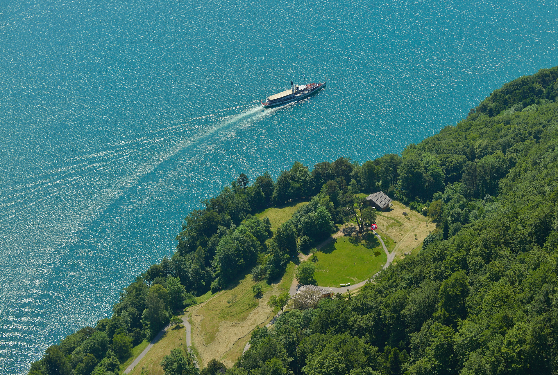 Bateau à moteur naviguant sur le lac des Quatre-Cantons le long des rives boisées de Seelisberg