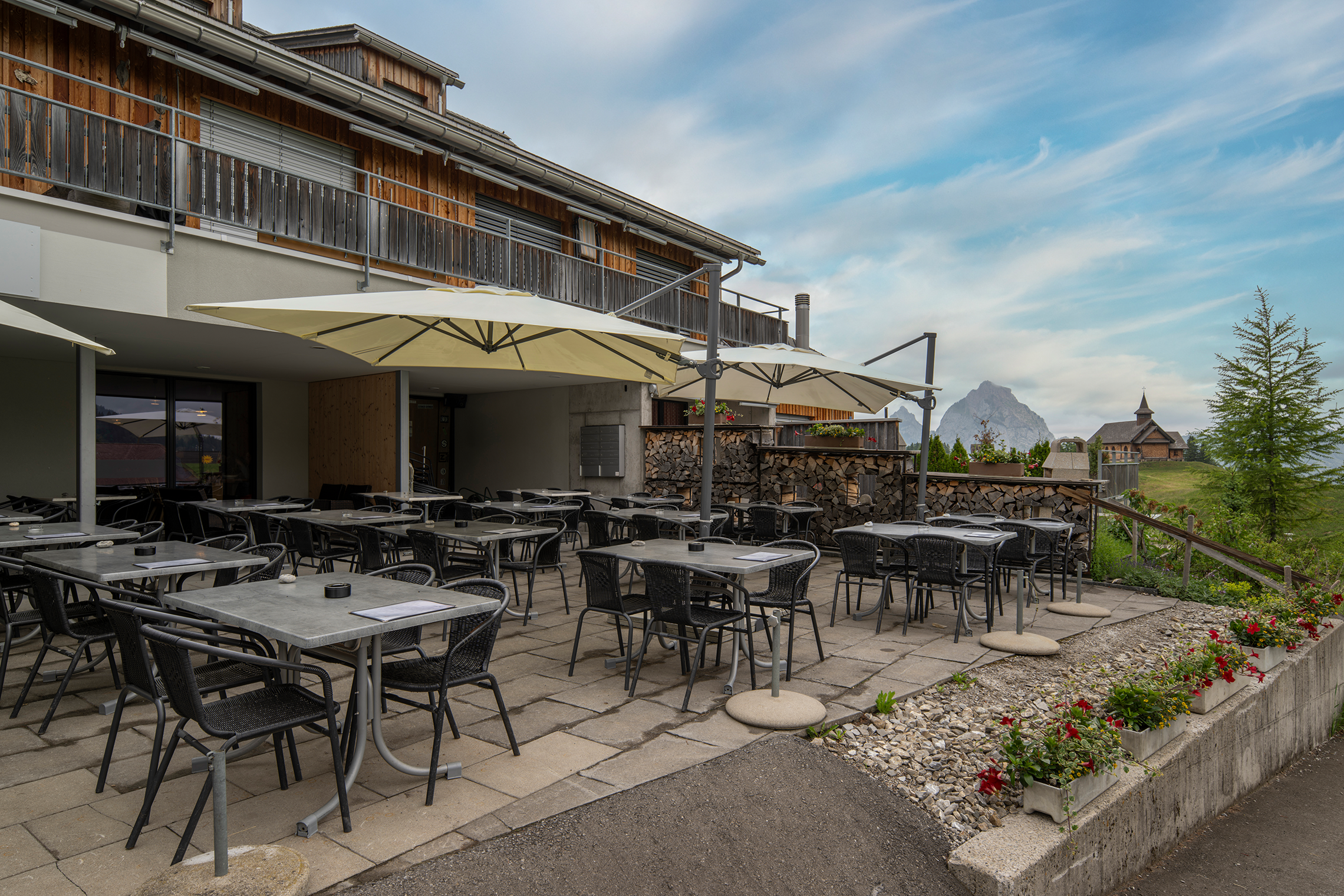 Restaurant terrace with seating and views of the alpine landscape.