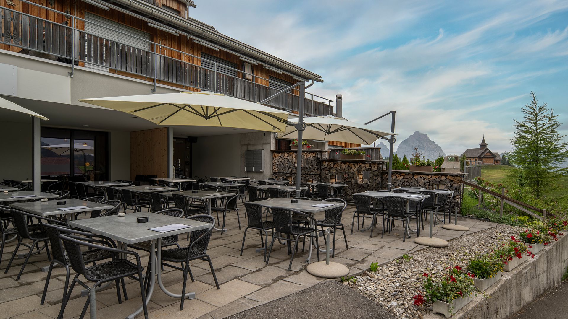 Restaurant terrace with seating and views of the alpine landscape.