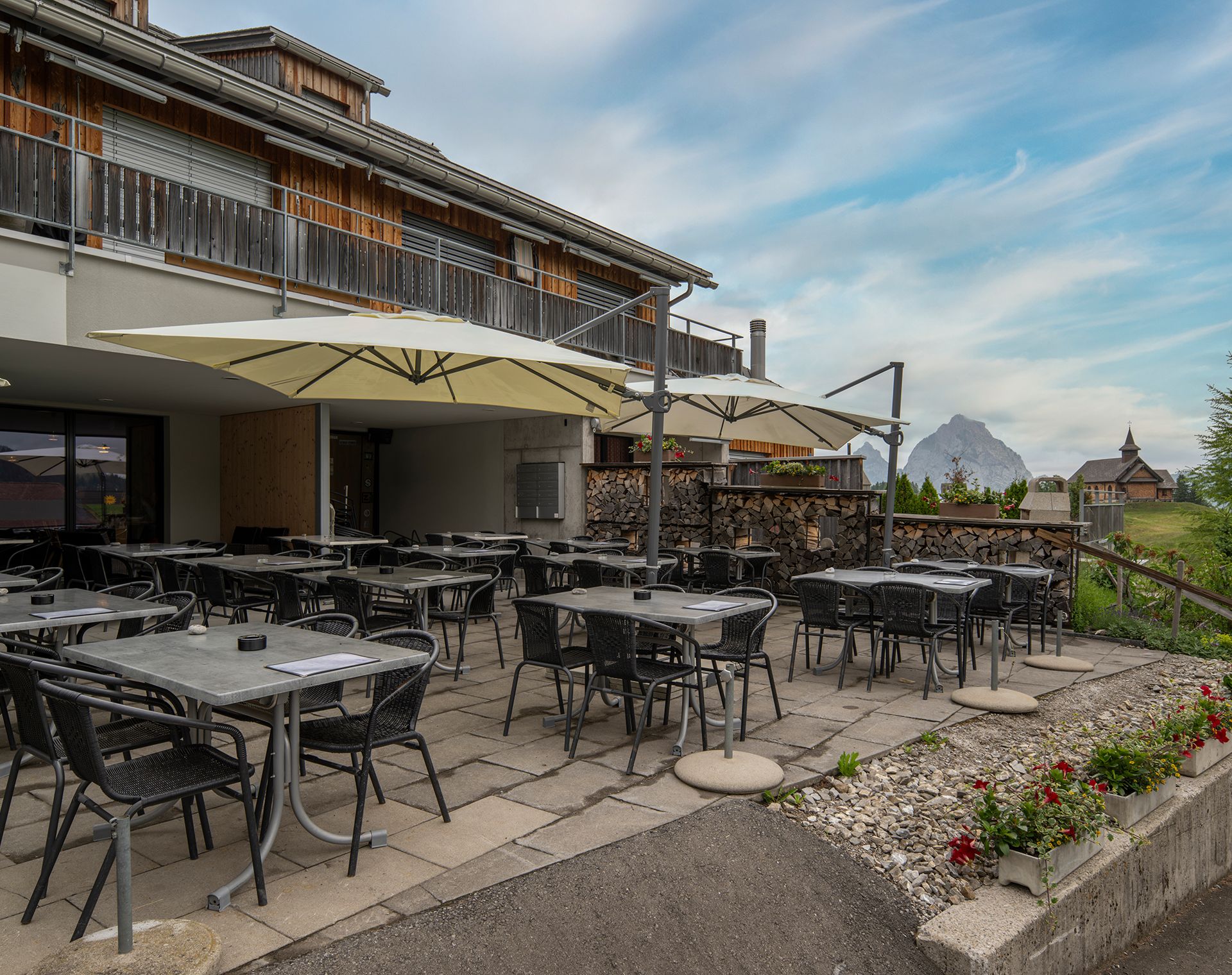 Restaurantterrasse mit Sitzplätzen und Blick auf die alpine Landschaft.