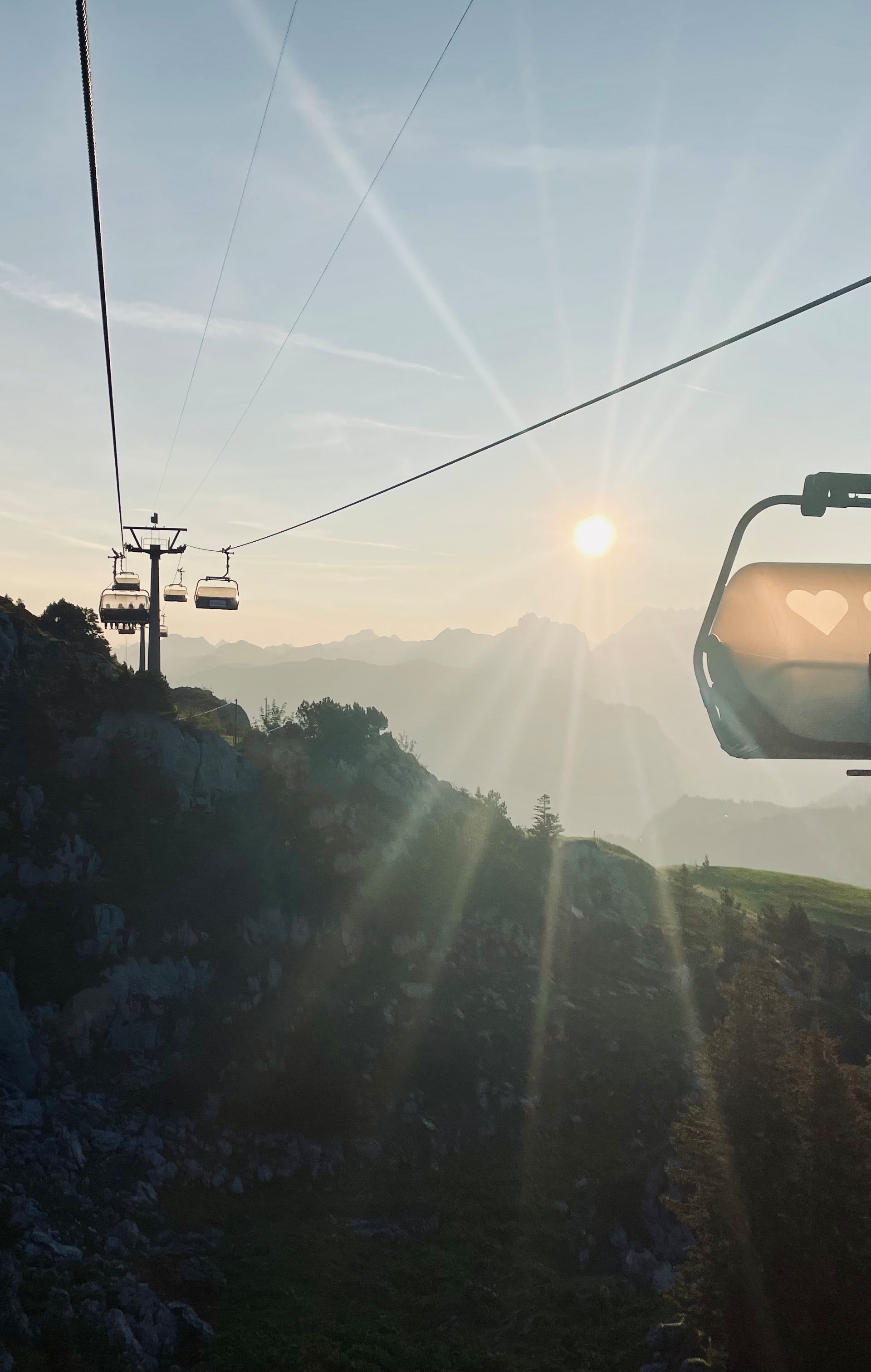 Sesselbahn am Fronalpstock im Gegenlicht der untergehenden Sonne, mit Blick auf die Berglandschaft.