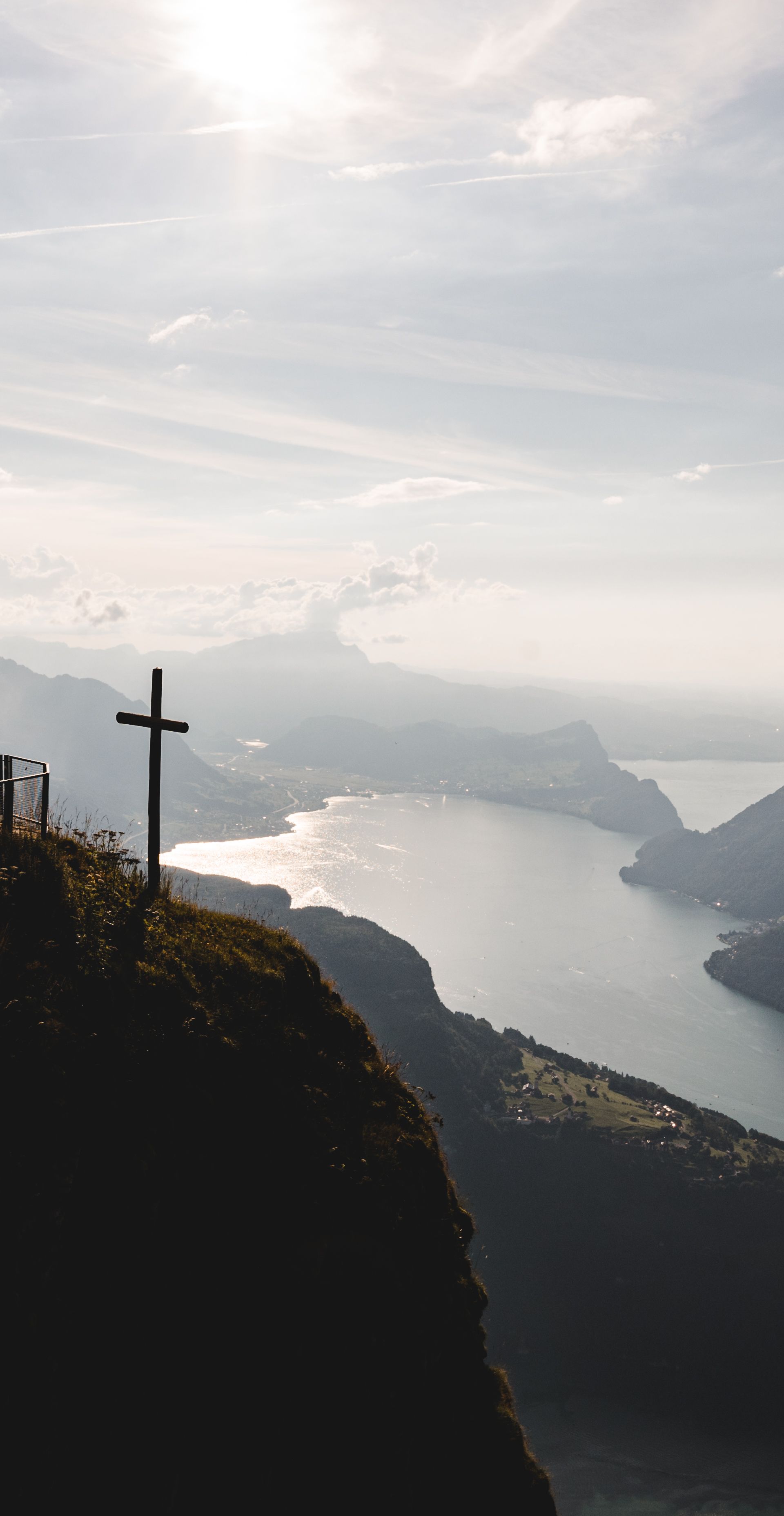 Aussichtsplattform mit Kreuz auf einem Felsvorsprung über dem Vierwaldstättersee im Gegenlicht.