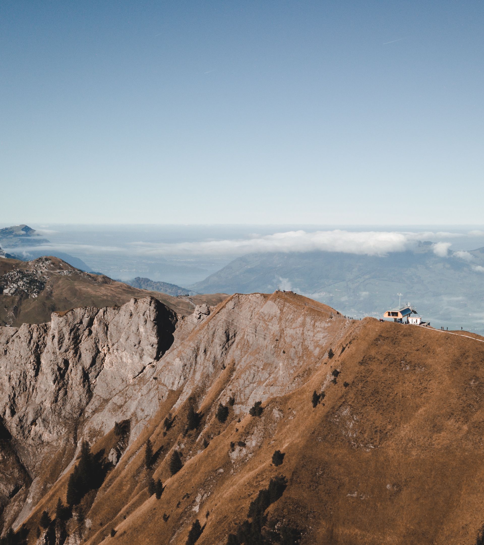 Felsiger Berggrat über den Wolken mit Blick auf die umliegende Alpenlandschaft.