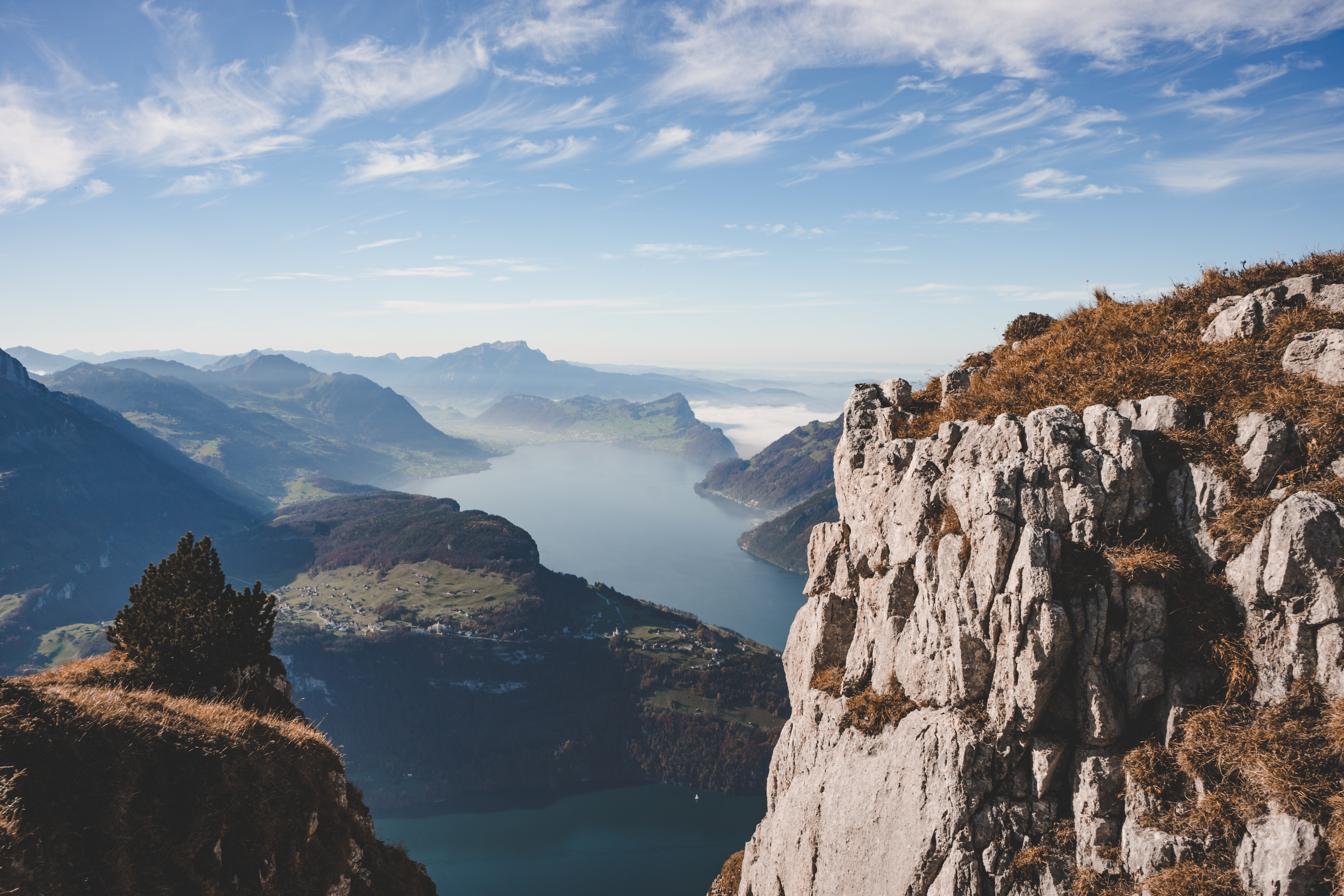 Rock formation on a mountain ridge overlooking Lake Lucerne and the surrounding alpine landscape.