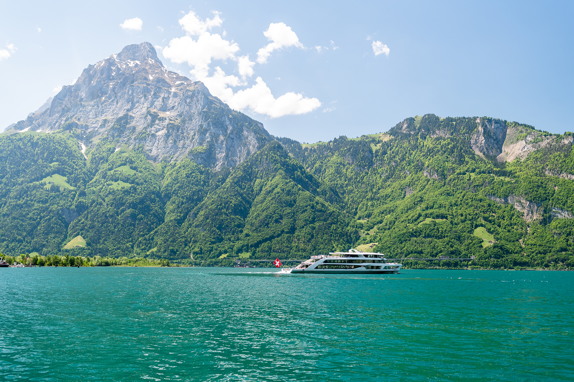 Bateau à moteur naviguant sur le lac des Quatre-Cantons devant les montagnes de la région de Seelisberg