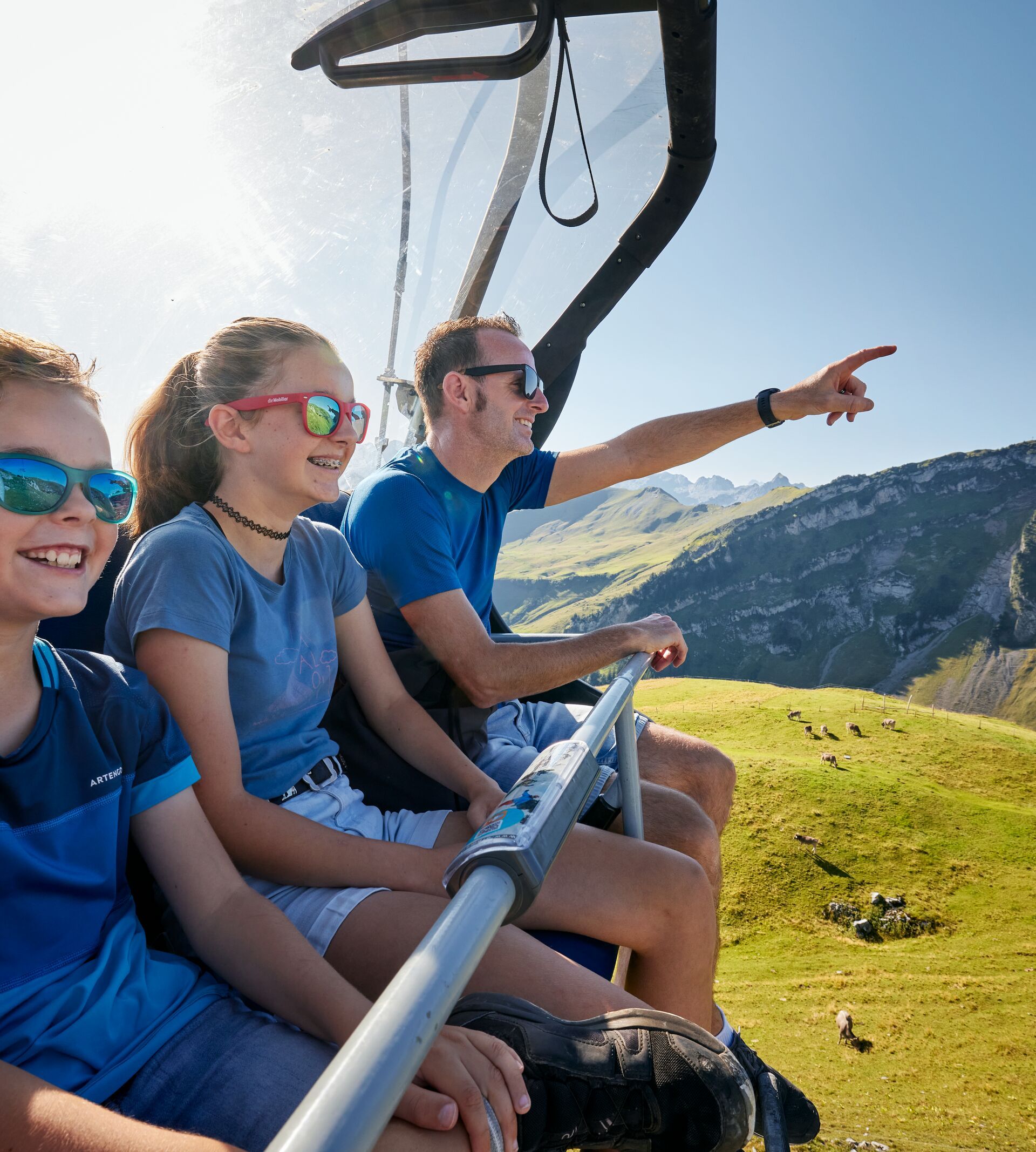 Family sitting on a chairlift enjoying the view of the mountain landscape.