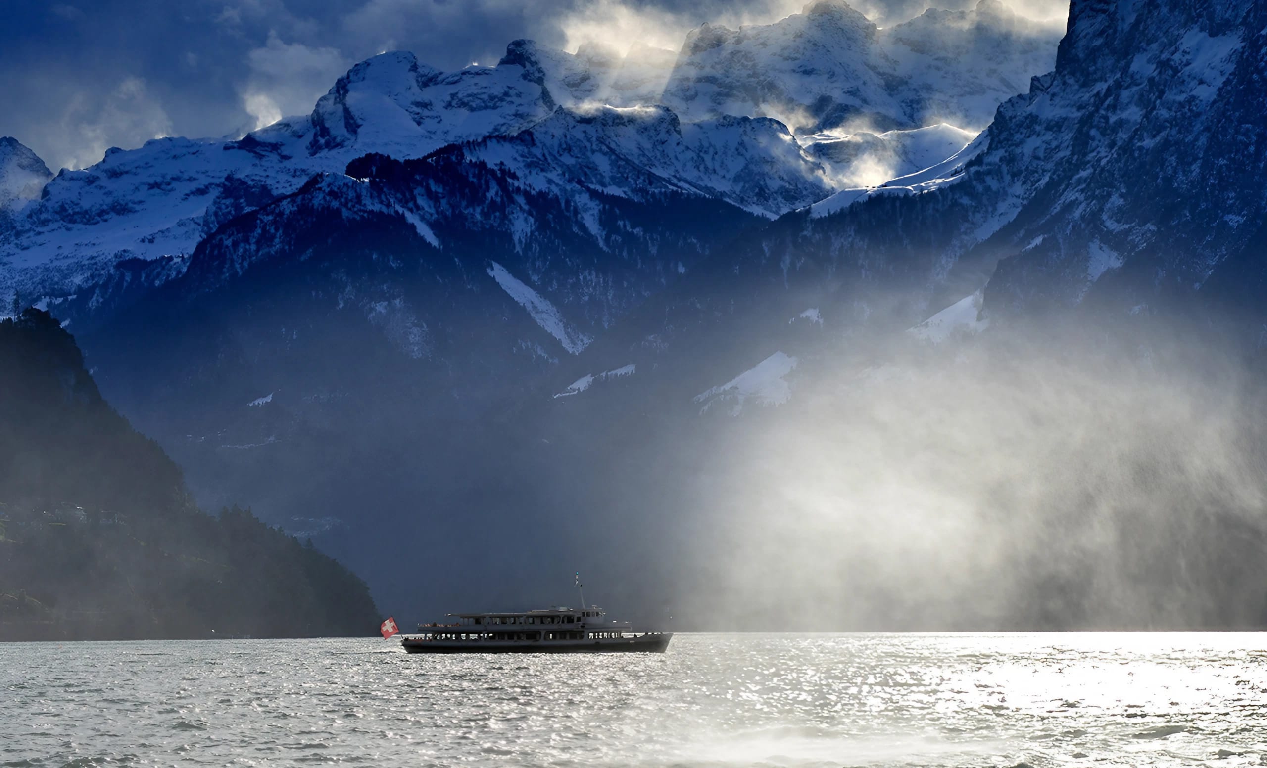 Image d'ambiance avec nuages et brouillard du lac des Quatre-Cantons en hiver avec un bateau à moteur.