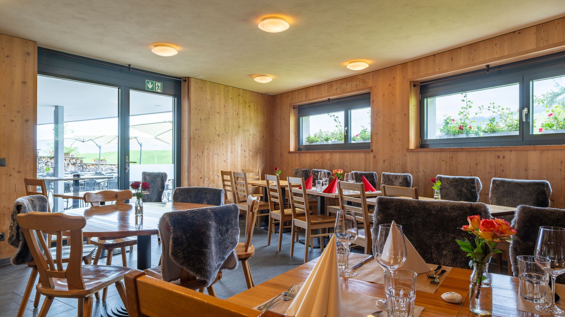 Restaurantinnenraum mit gedeckten Tischen und Blick durch grosse Fenster auf die Berglandschaft.