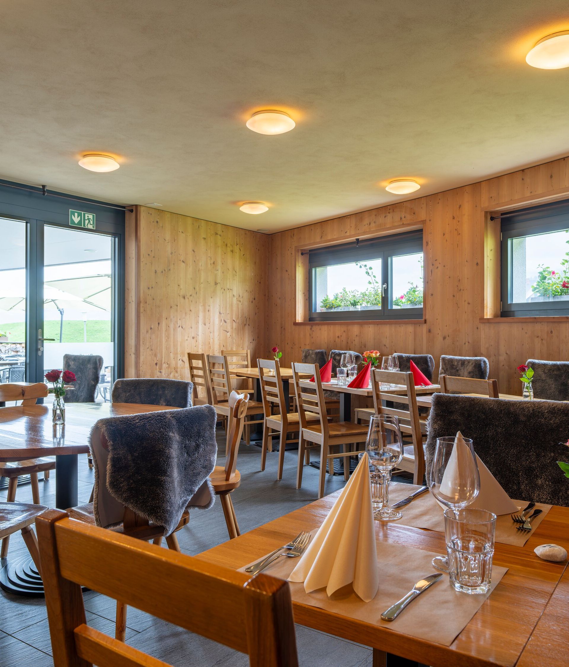 Restaurantinnenraum mit gedeckten Tischen und Blick durch grosse Fenster auf die Berglandschaft.