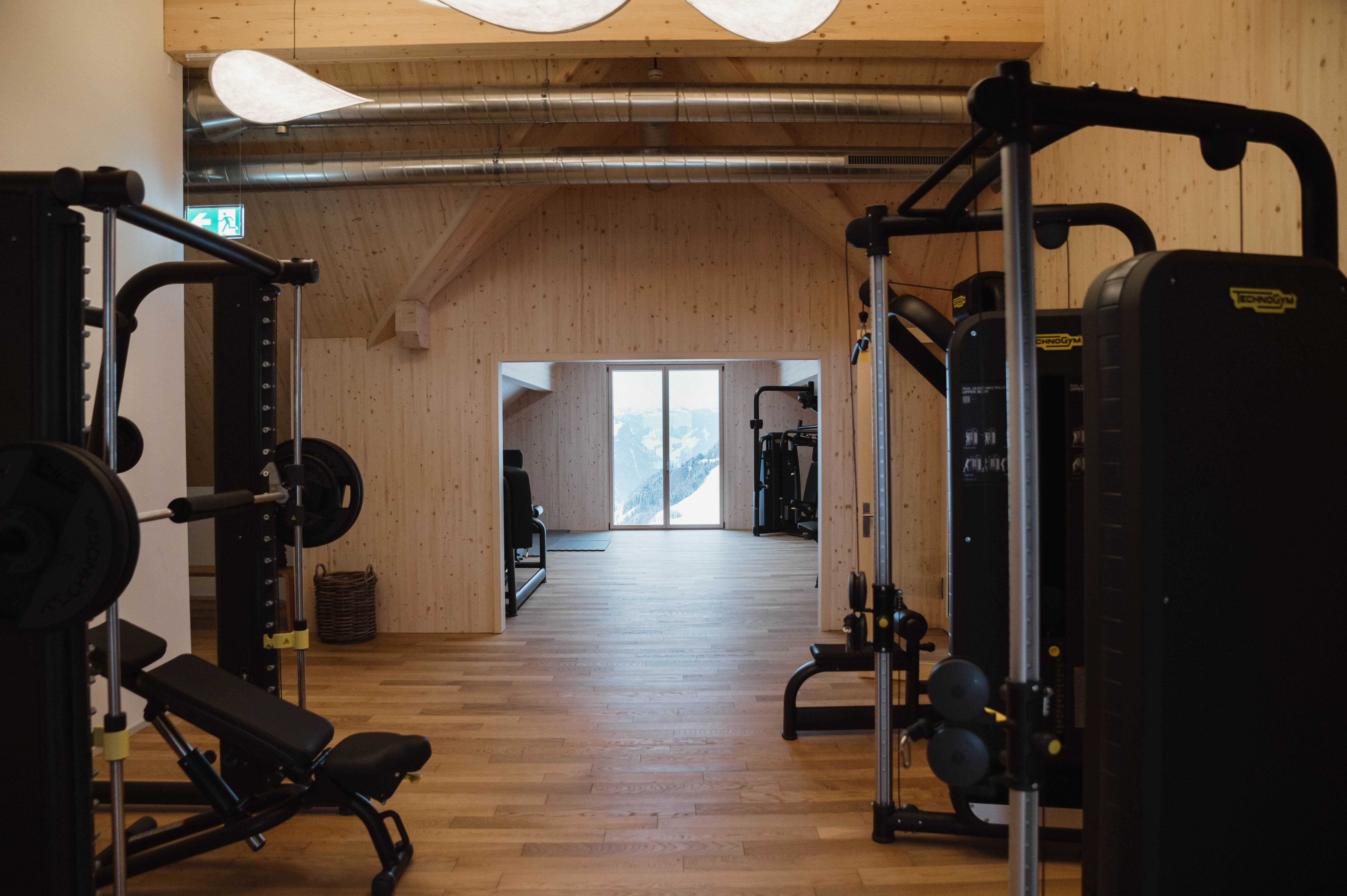 Fitnessraum mit Kraftgeräten und freiem Trainingsbereich in modernem Ambiente.