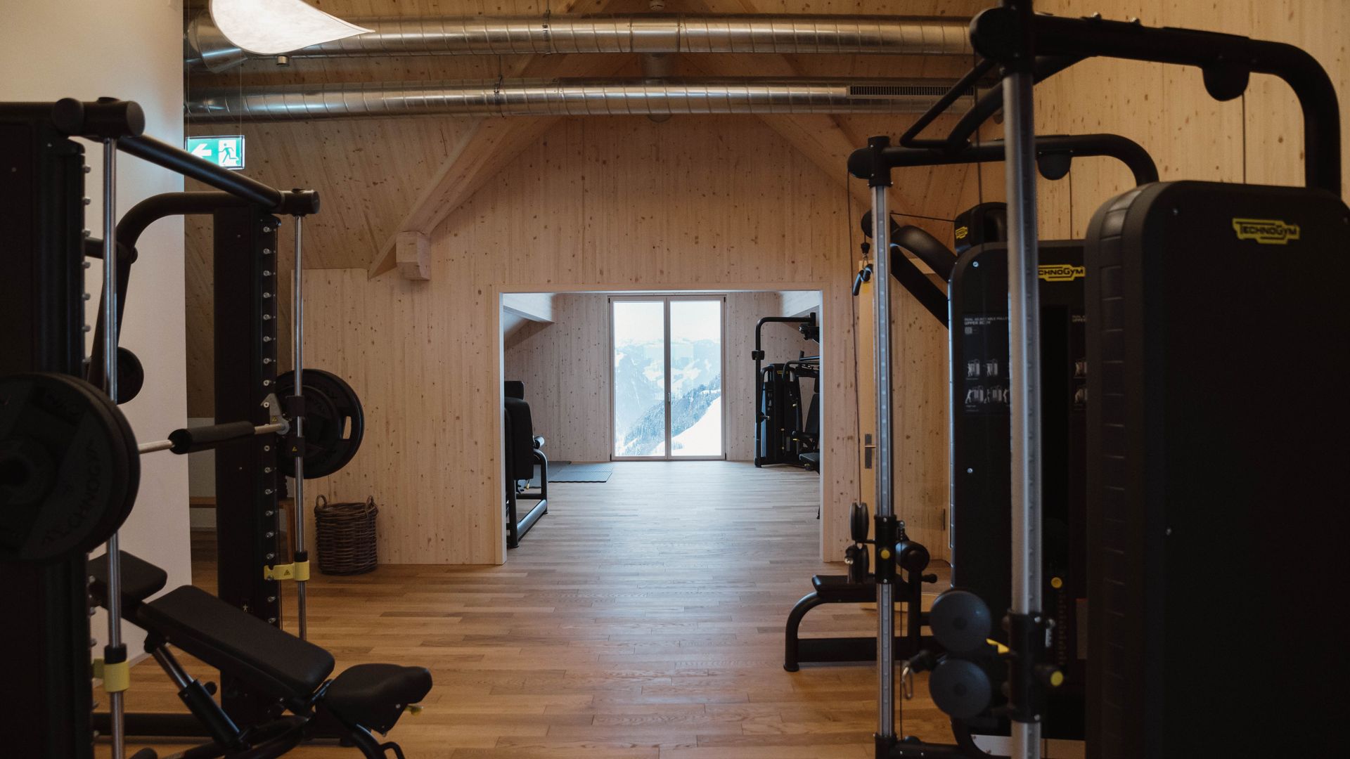 Fitnessraum mit Kraftgeräten und freiem Trainingsbereich in modernem Ambiente.