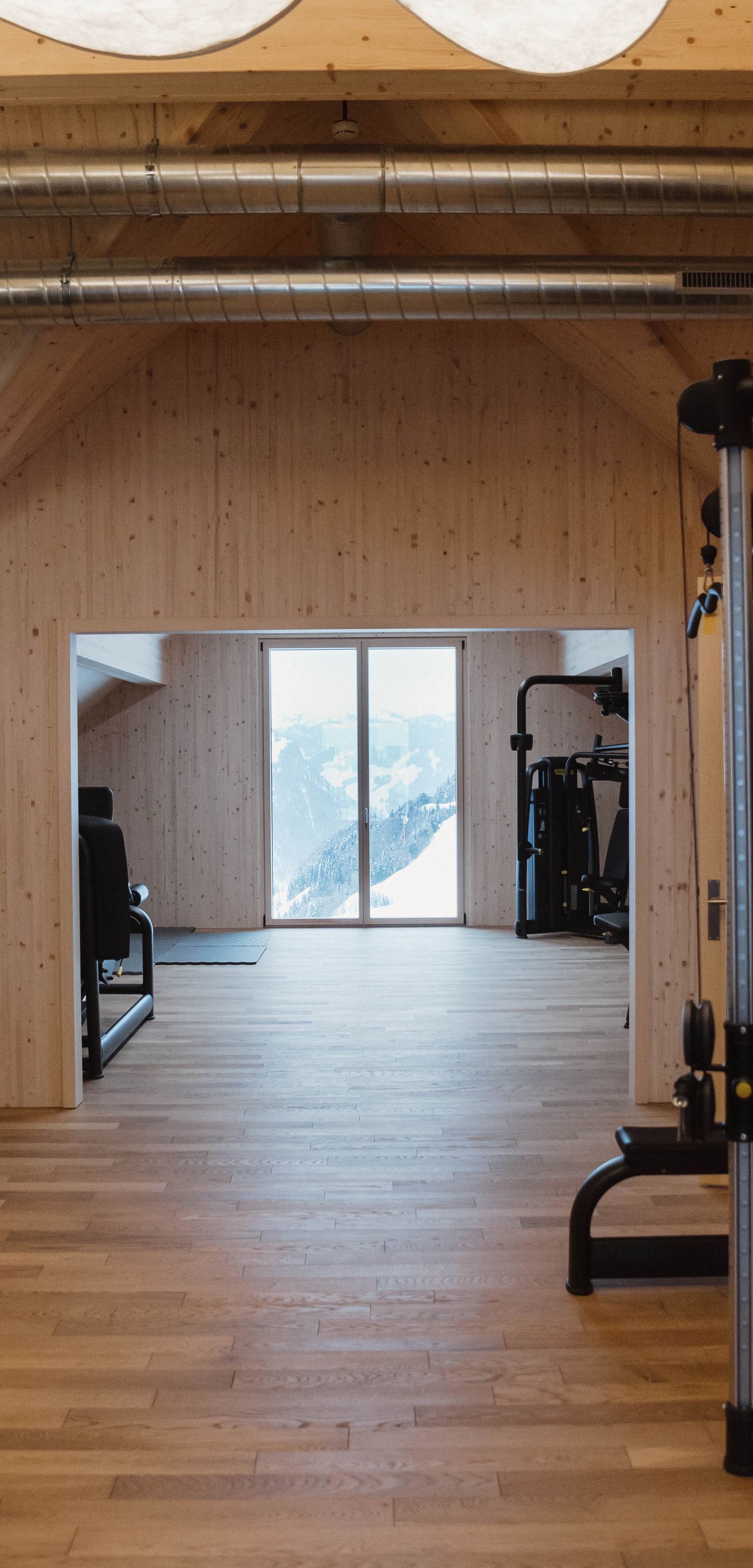 Fitnessraum mit Kraftgeräten und freiem Trainingsbereich in modernem Ambiente.