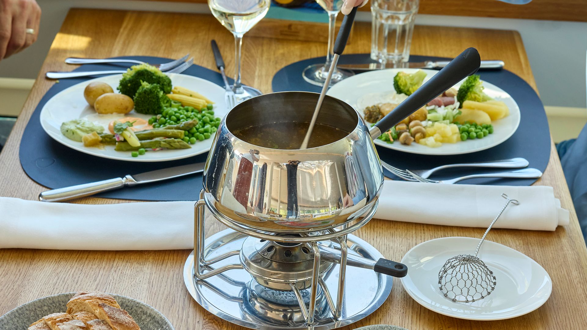 Fondue chinoise accompagnée de garnitures printanières et de spécialités de viande suisse servie à bord d’un bateau sur le lac des Quatre-Cantons