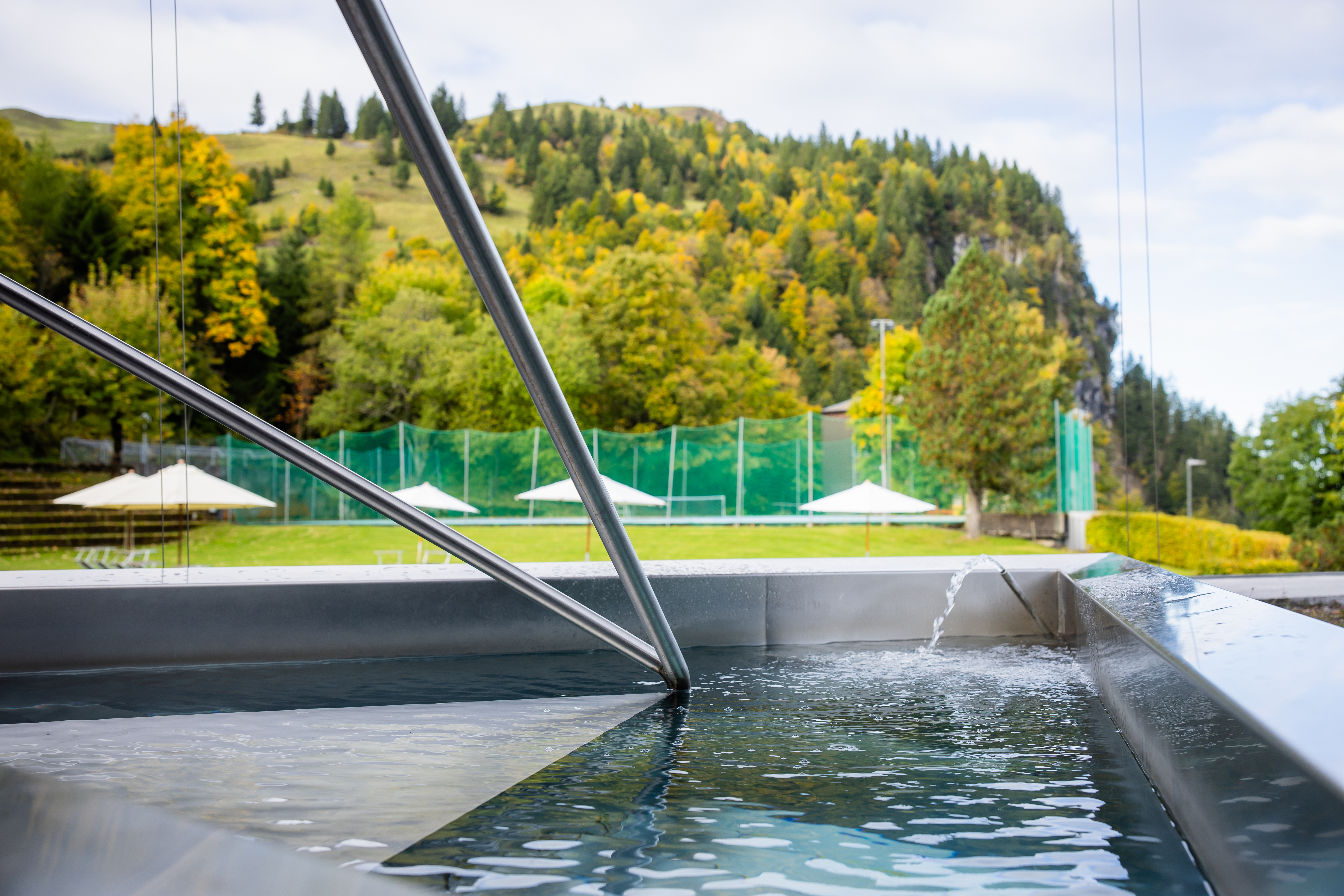 Outdoor pool with a view of green hills and forest landscape.
