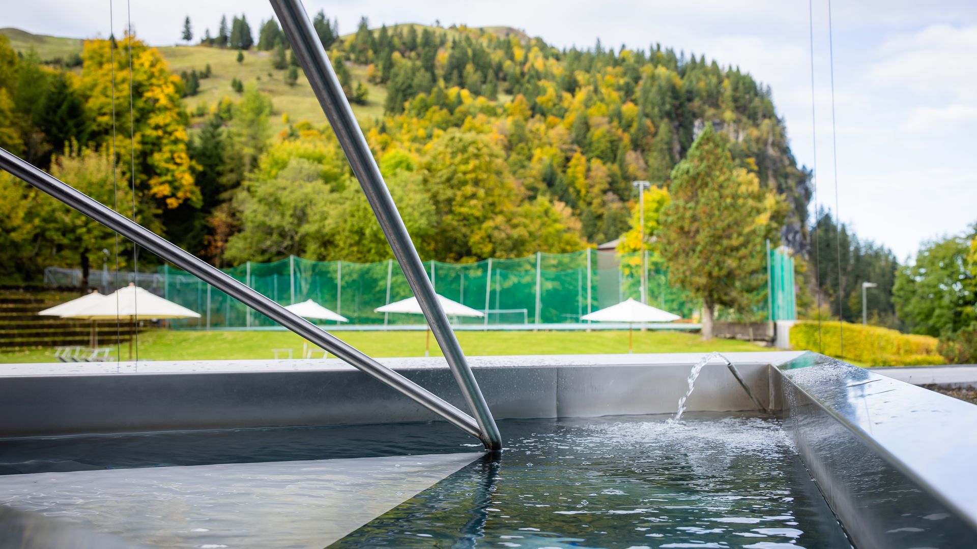 Outdoor pool with a view of green hills and forest landscape.