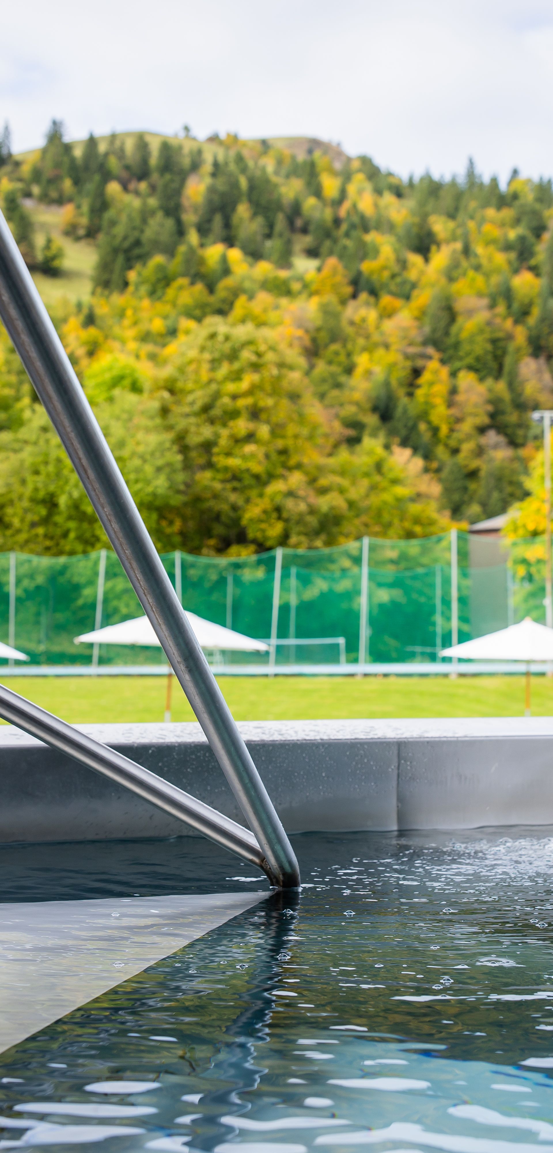 Aussenpool mit Blick auf grüne Hügel und Waldlandschaft.