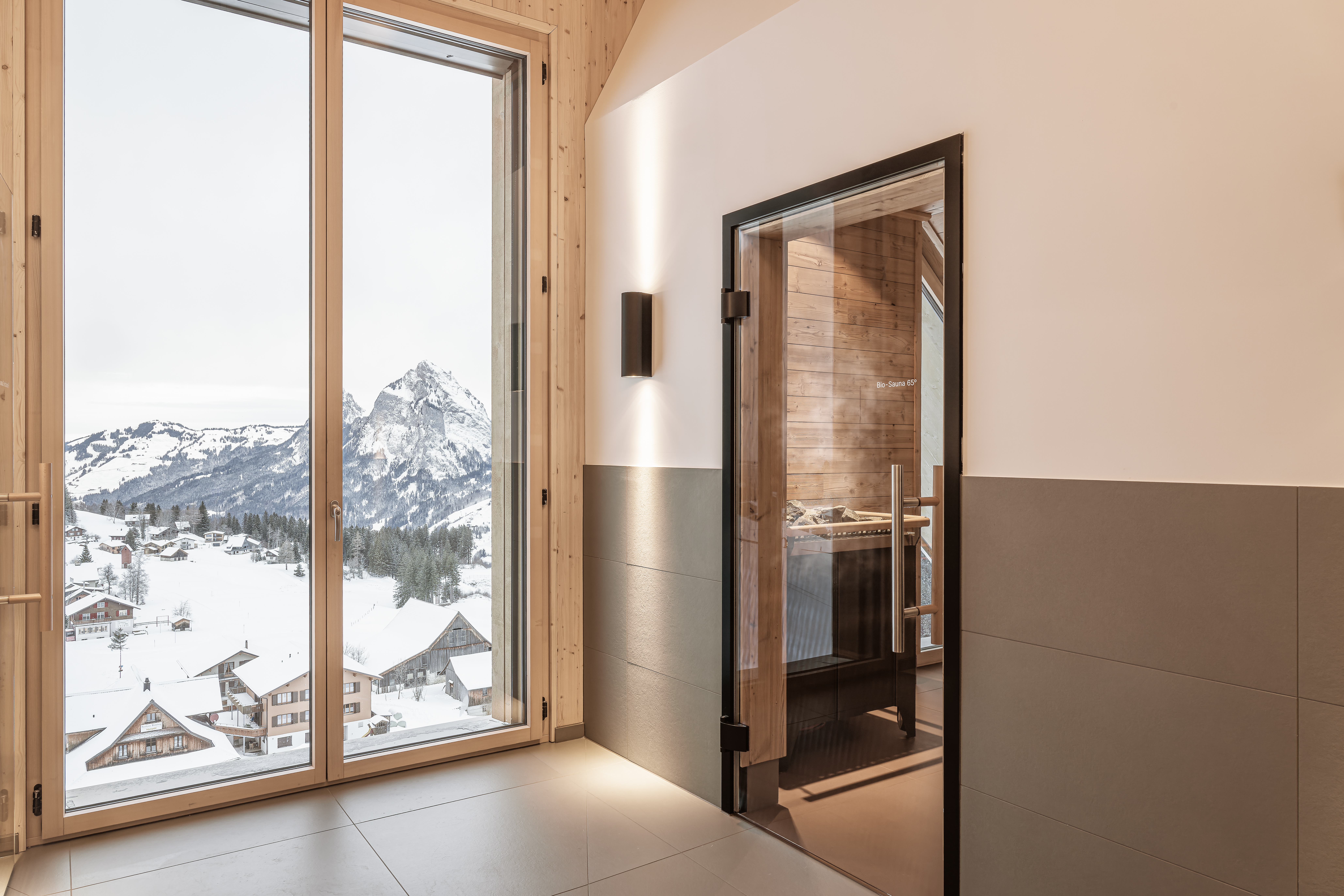 Heller Innenbereich mit Blick auf verschneite Berglandschaft und Zugang zur Sauna.
