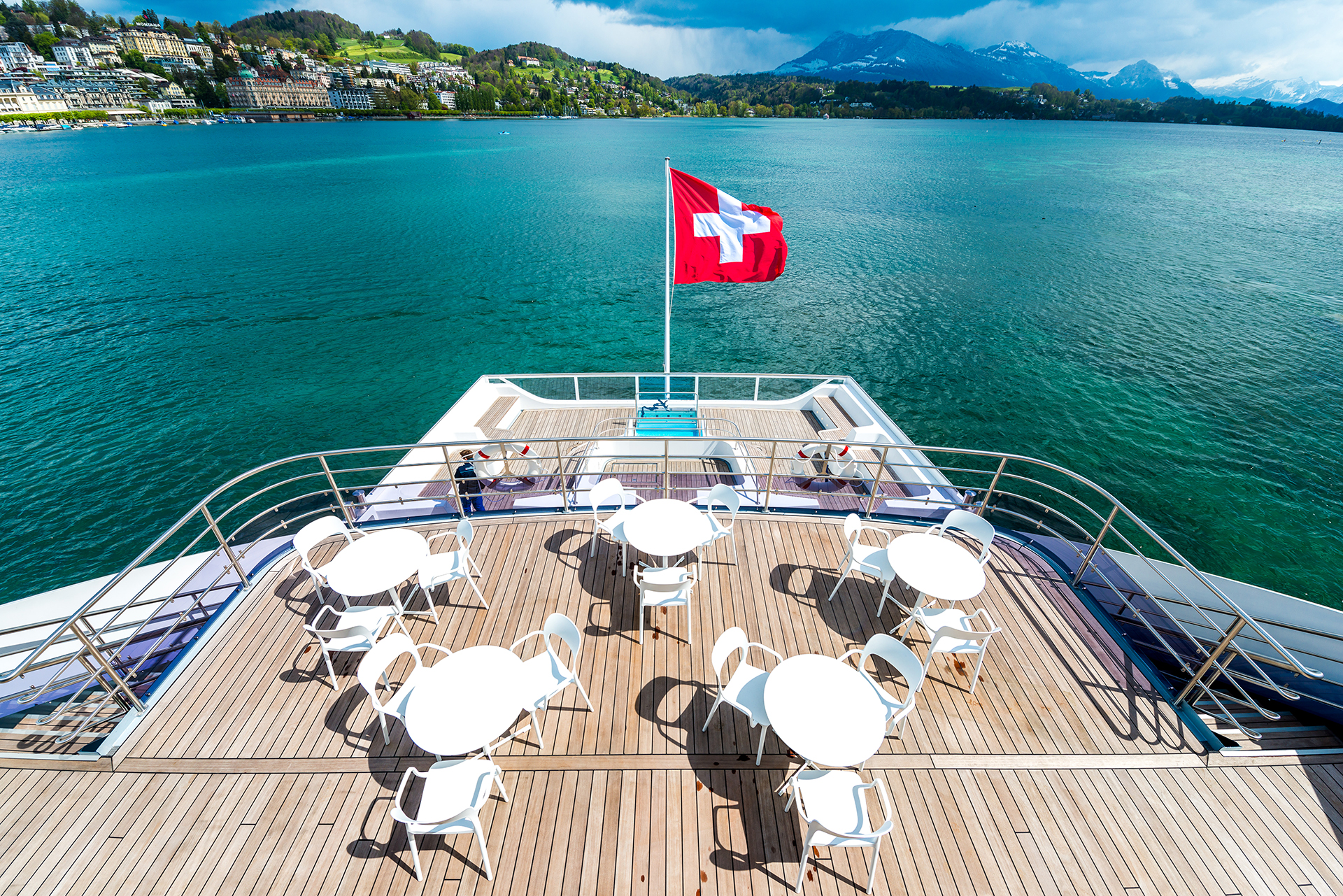 Spacious sun deck on a Lake Lucerne vessel with seating areas and a Swiss flag