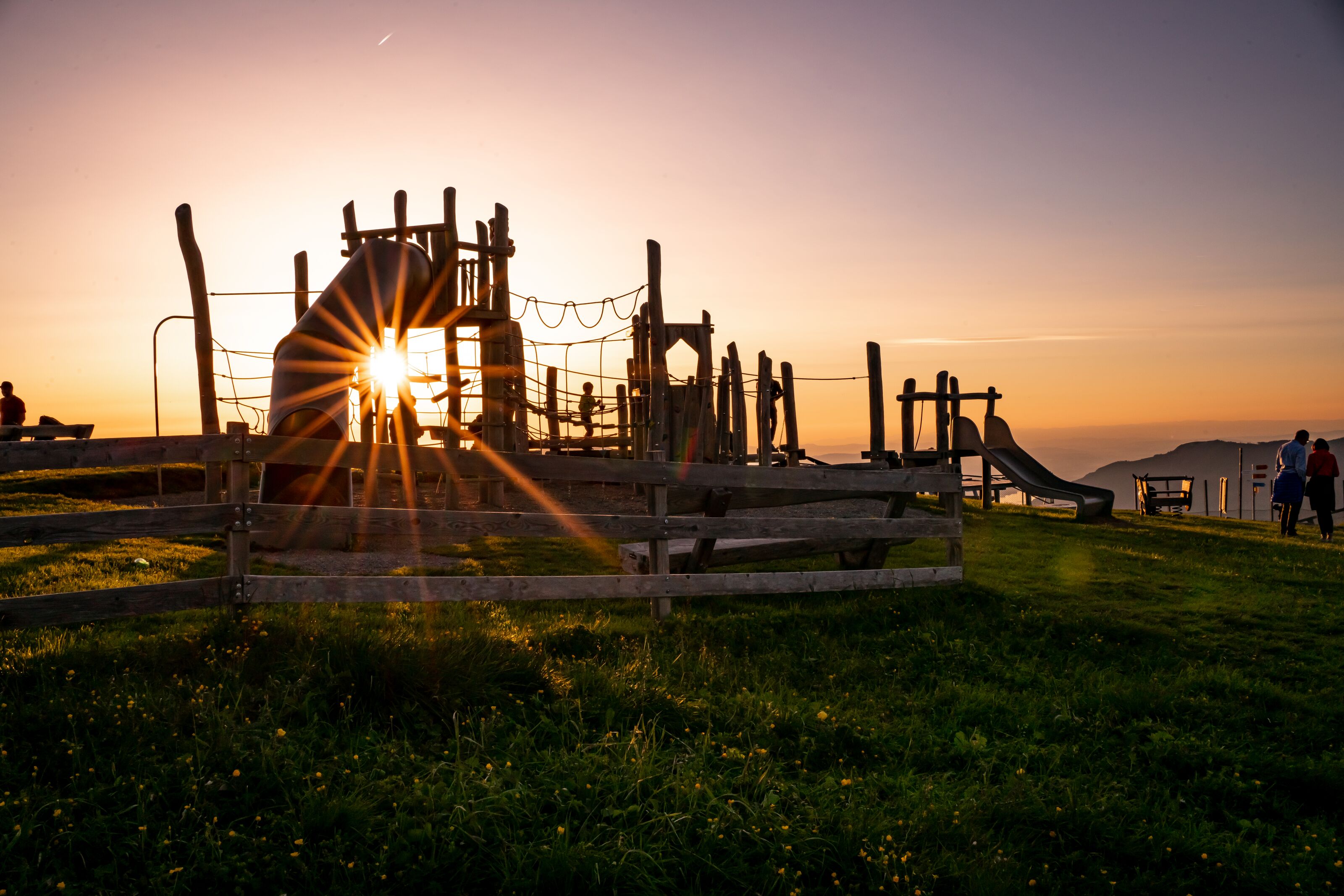 Playground on a mountain meadow at sunset with views of the Alps.