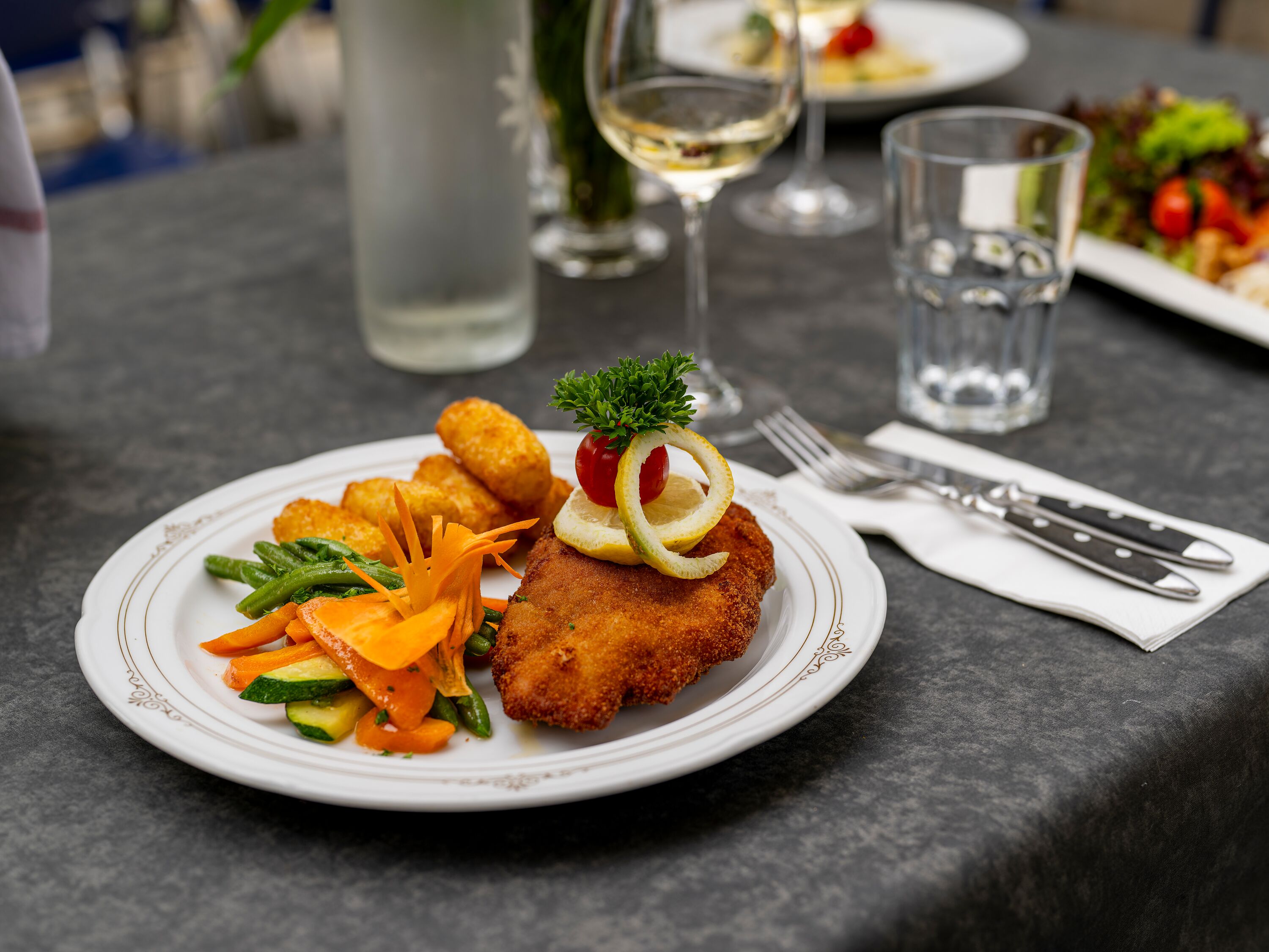 Servierter Teller mit Hauptgericht und Gemüse auf einem gedeckten Tisch im Restaurant.