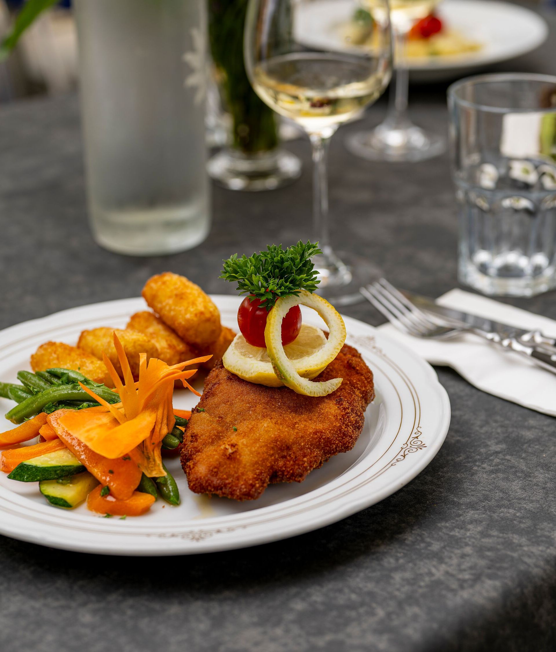 Servierter Teller mit Hauptgericht und Gemüse auf einem gedeckten Tisch im Restaurant.