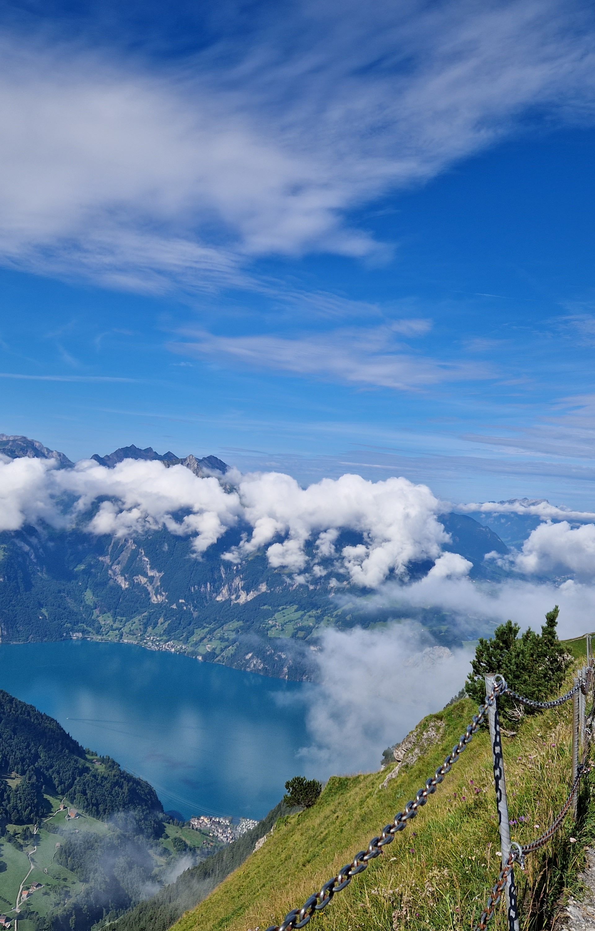 Mountain ridge trail overlooking Lake Lucerne, surrounded by clouds and alpine landscape.