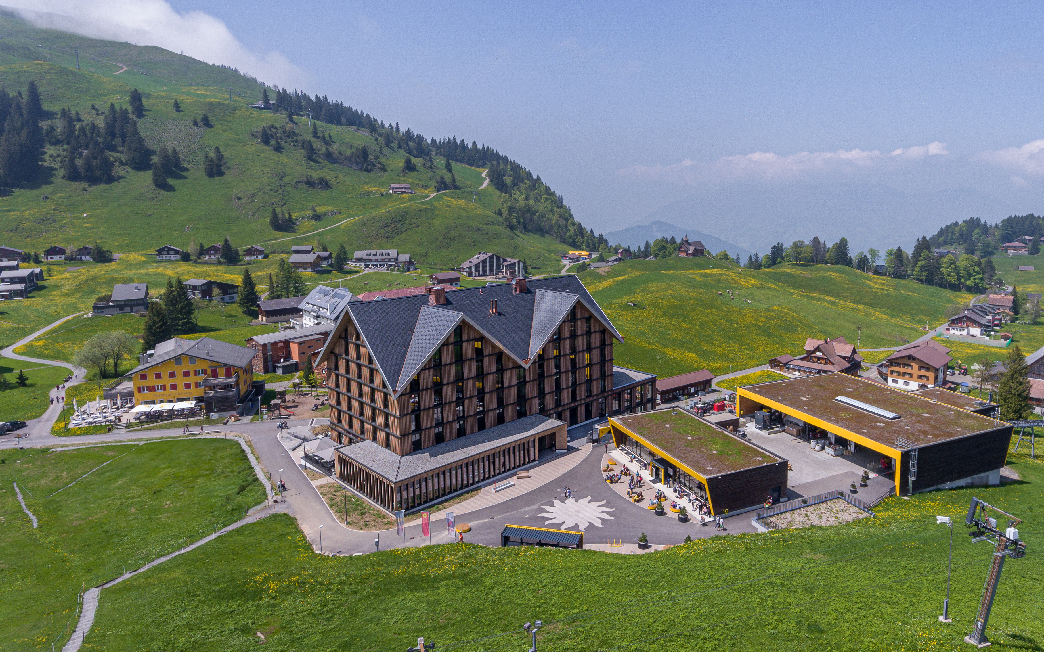 Hotel on Stoos next to the mountain station with modern architecture and surrounding alpine landscape.