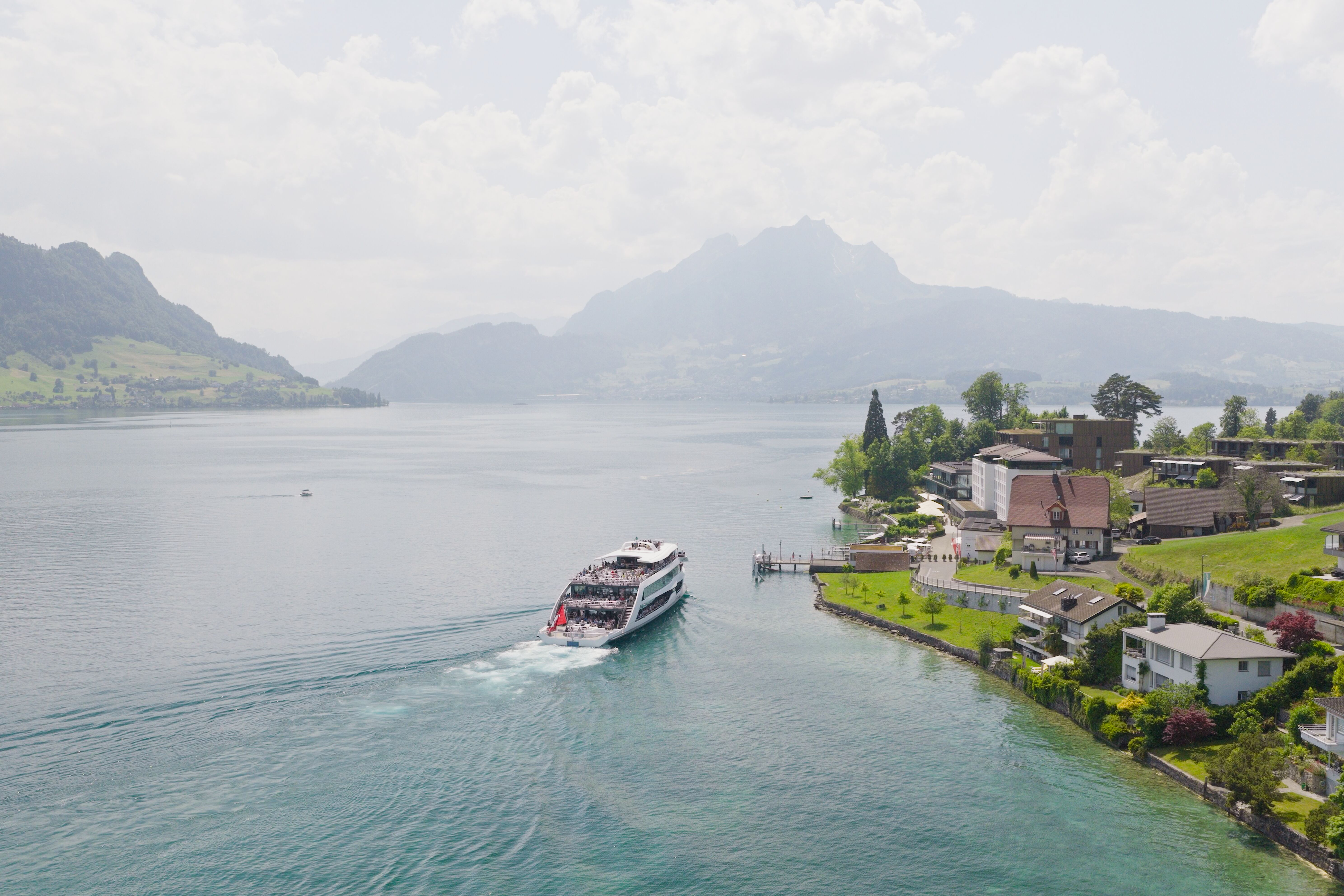Motor vessel Diamant approaching Hertenstein pier on Lake Lucerne with mountains and lakeside scenery in the background