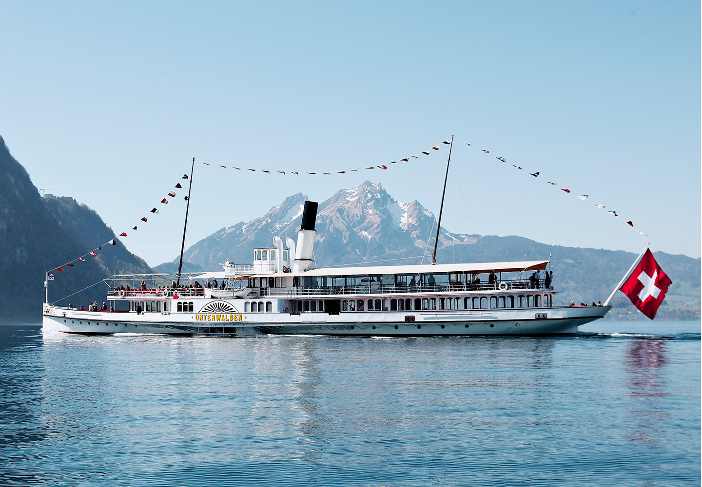 Steamboat with festive flag on Lake Lucerne with Mount Pilatus in the background