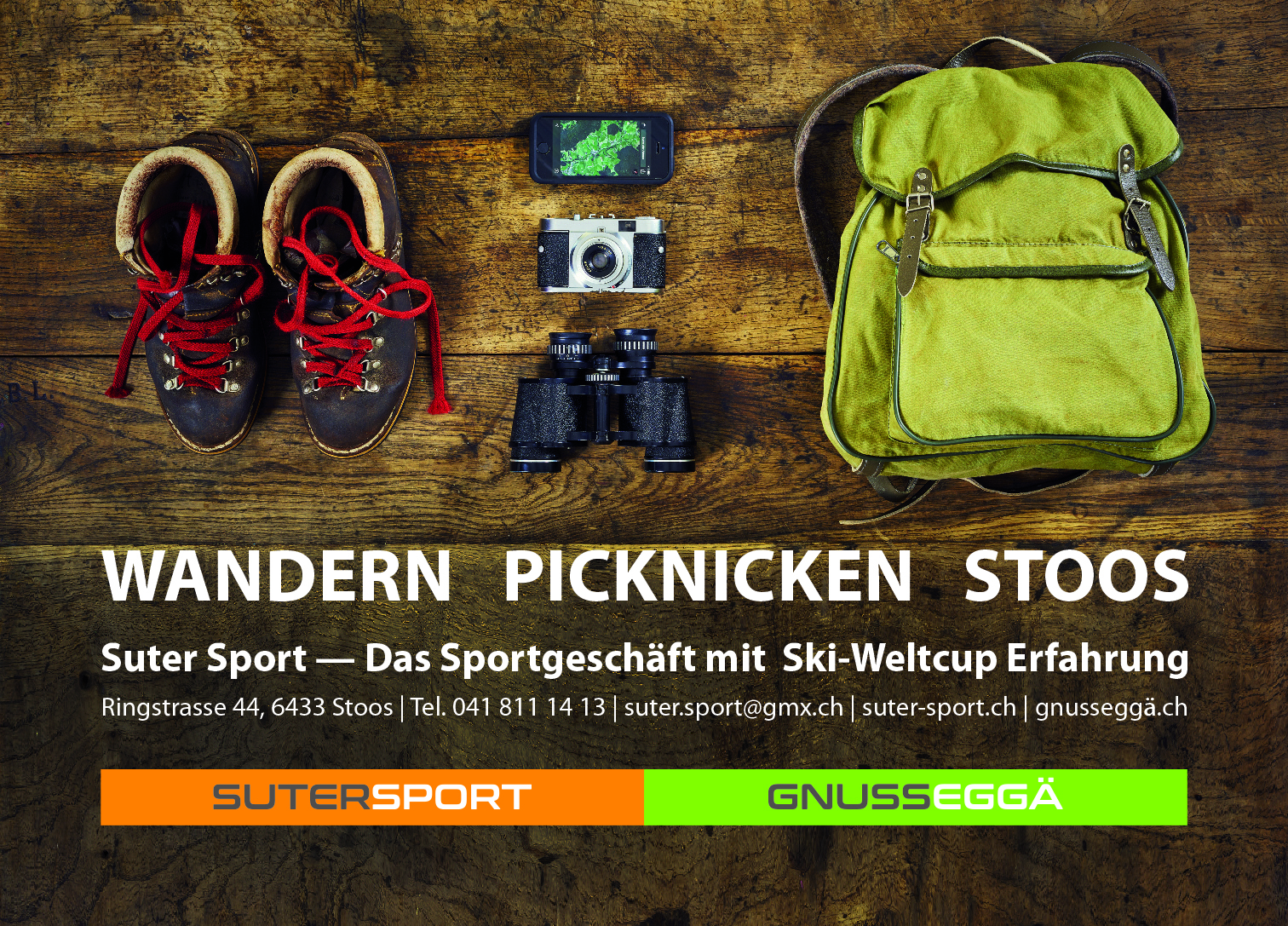 Hiking and picnic gear including shoes, backpack, camera, and binoculars on a wooden surface, with promotional text for Suter Sport Stoos.